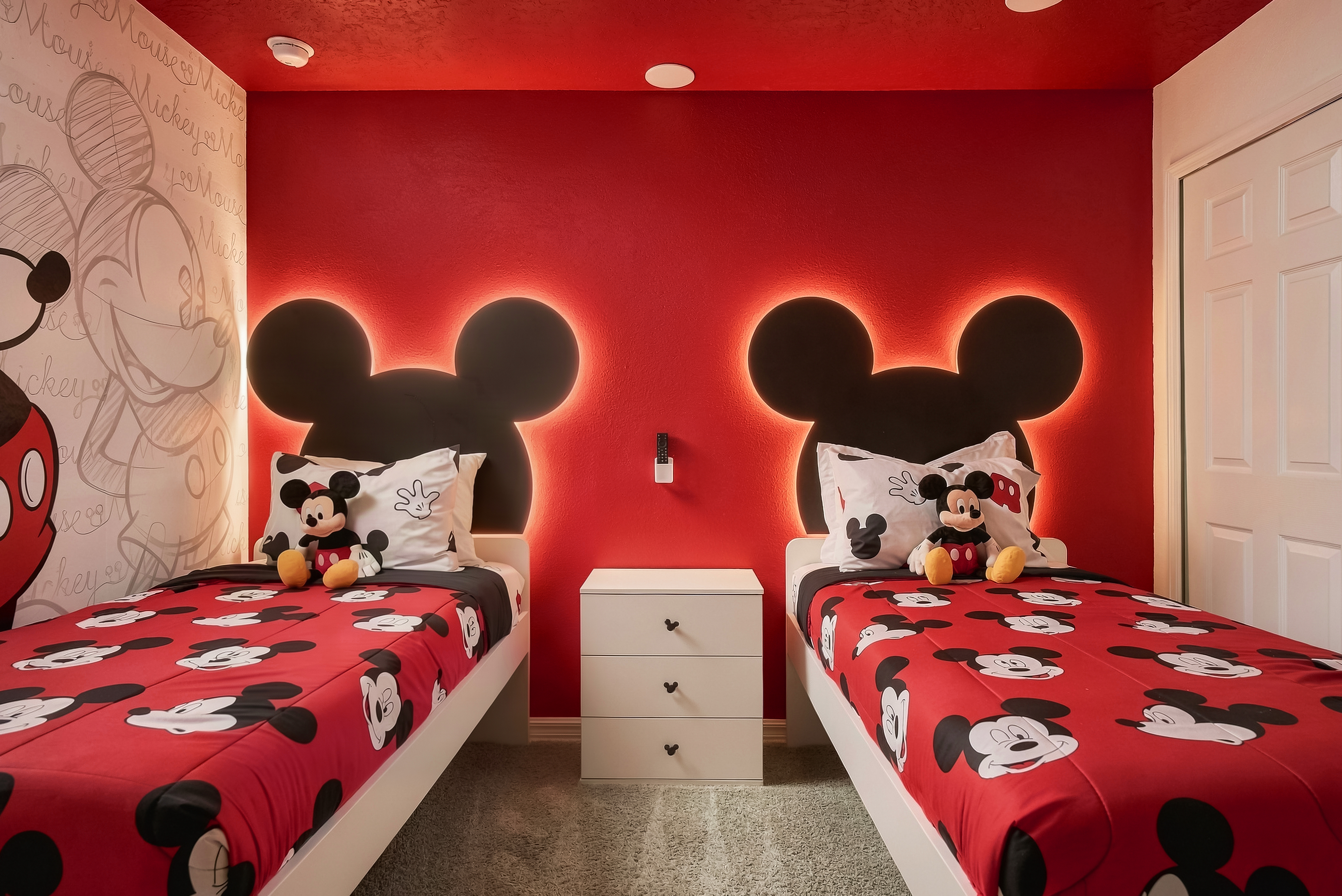 Bedroom 5-The Mickey Mouse room the whole family loves — two twin beds with lighted Mickey-ear headboards, playful character bedding, and a fun mural wall. Kids race straight here after the parks.