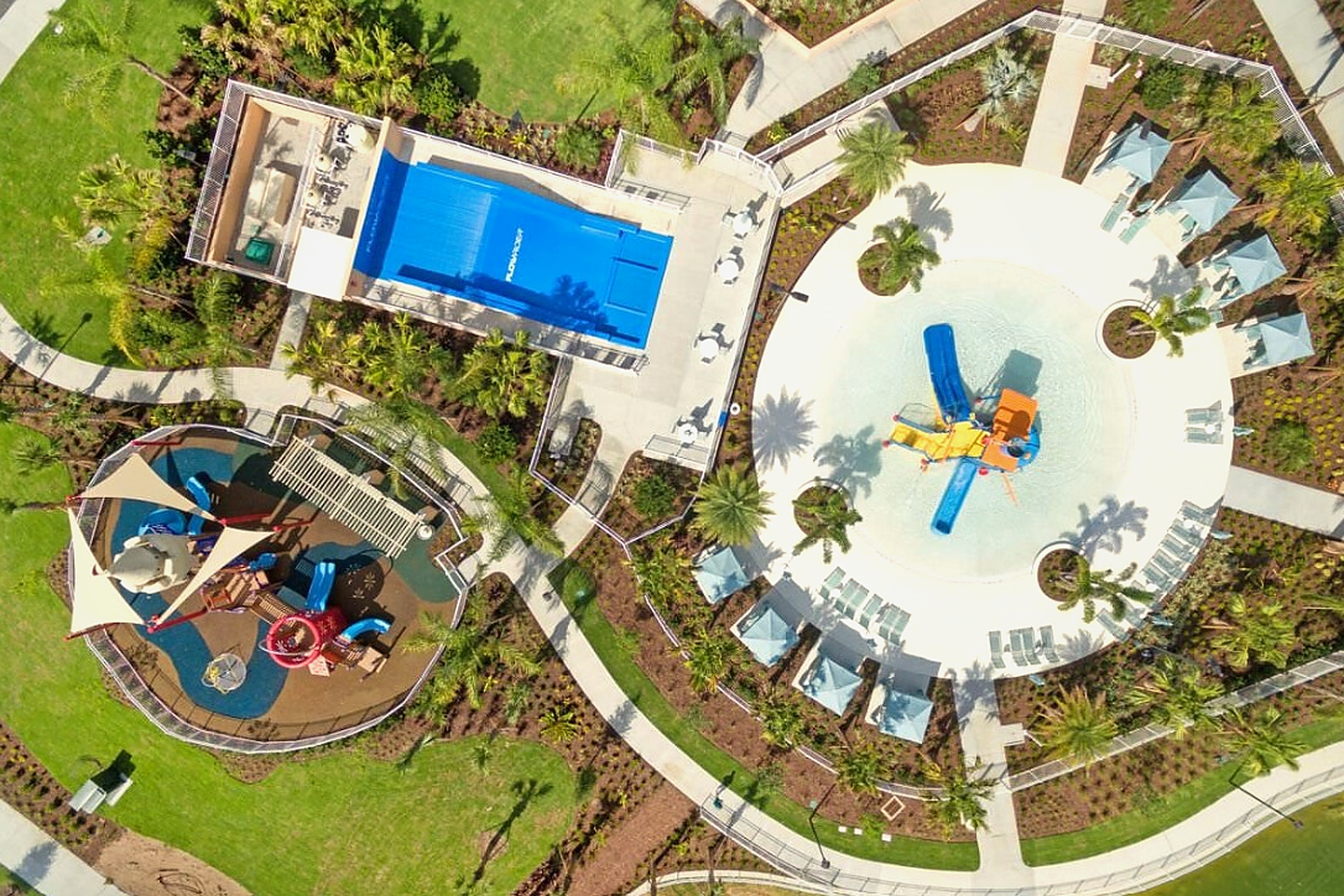 Resort-style pool, splash pad, and playground in a lush tropical setting