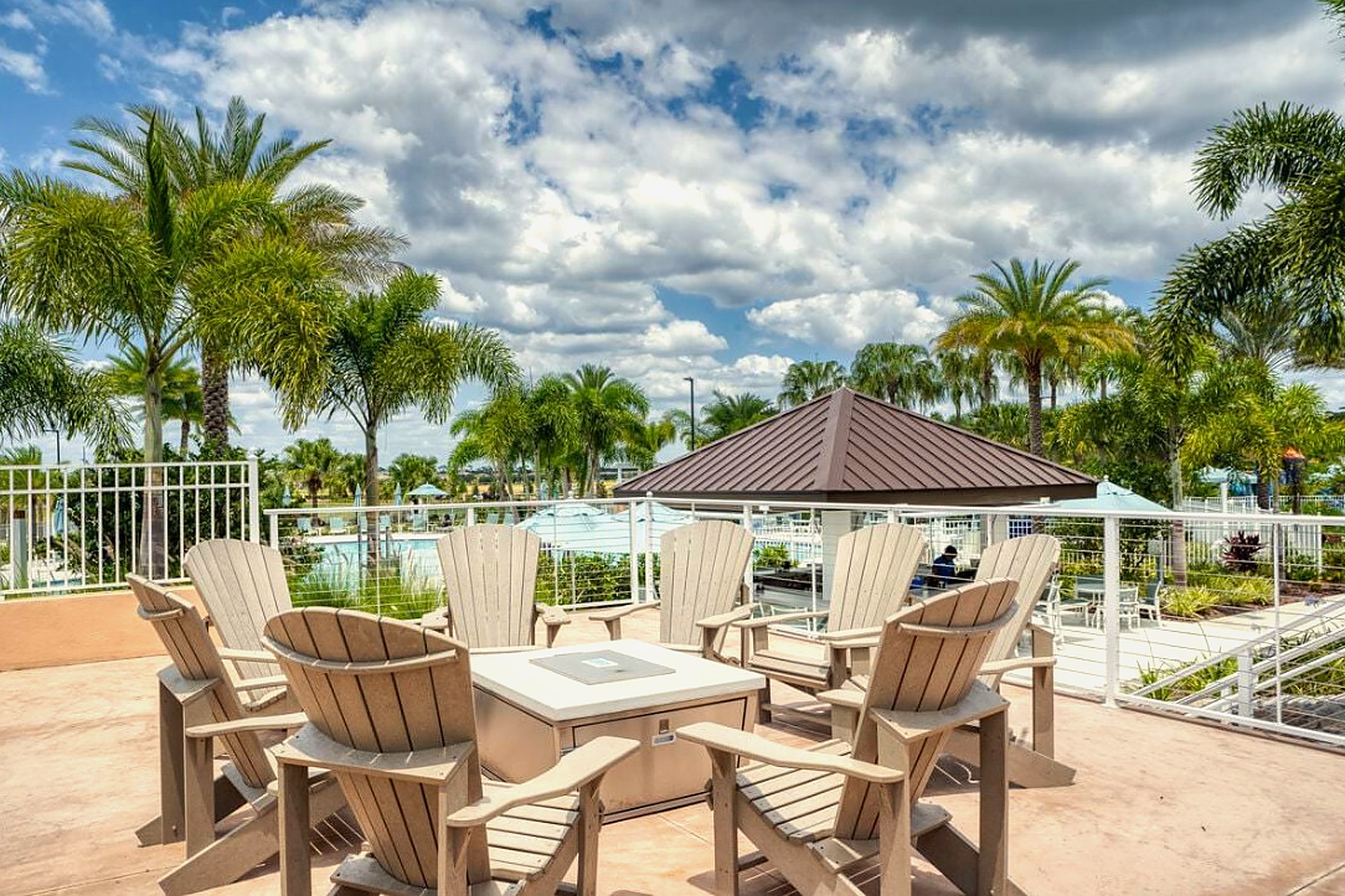 Tropical poolside fire pit lounge with palm views and resort-style seating