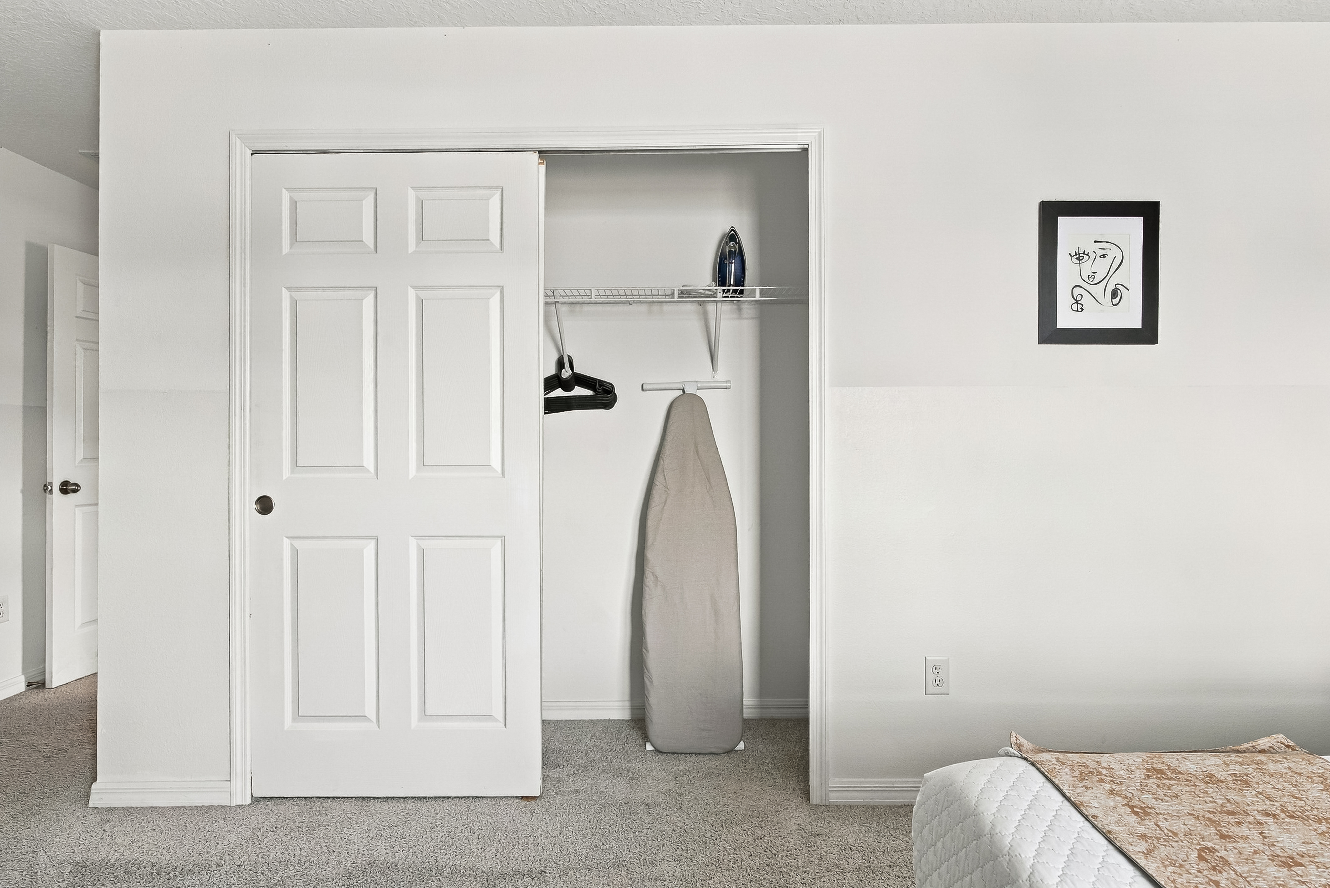 Bedroom closet with guest storage, hangers, and ironing board