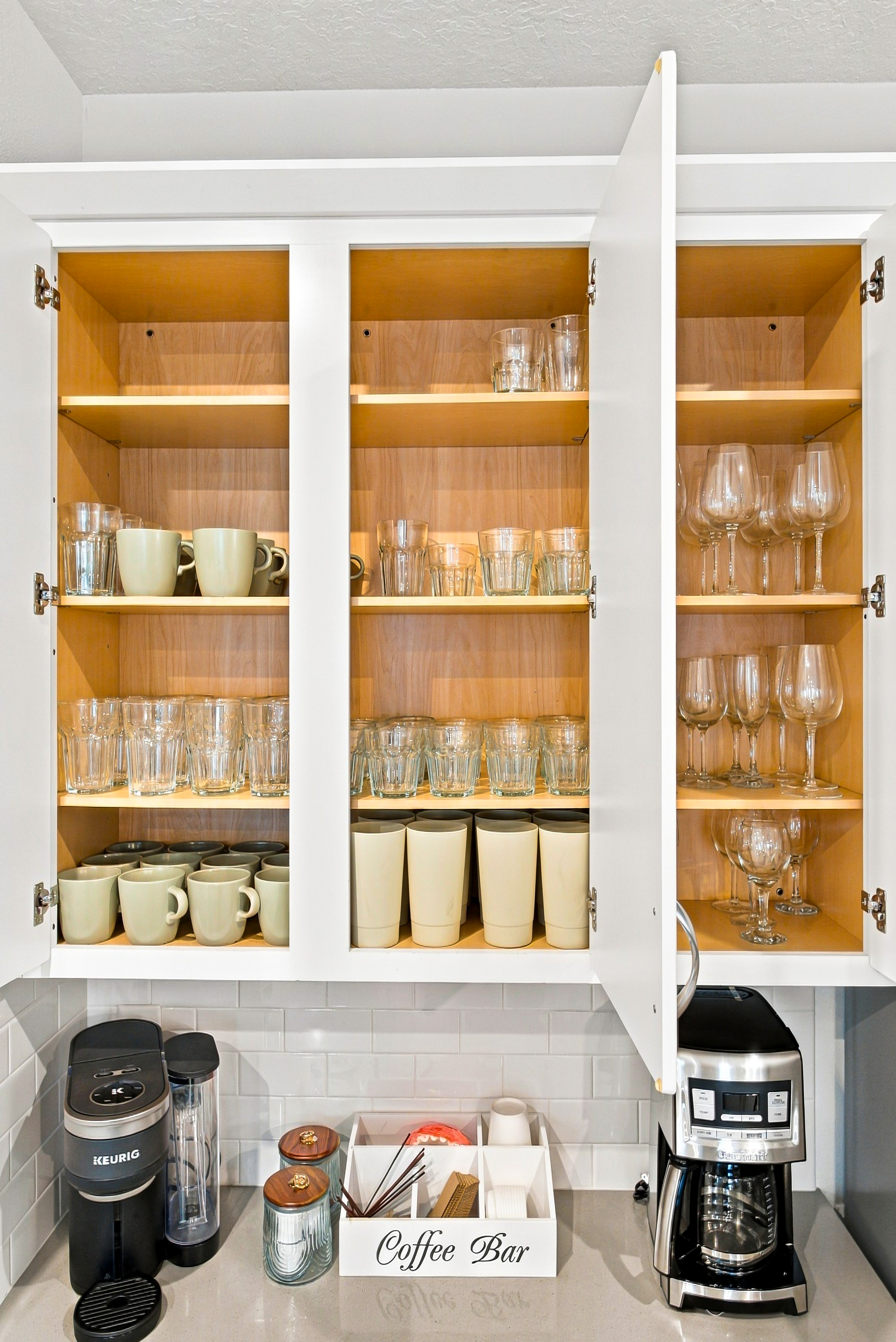 Well-stocked coffee bar with mugs, glassware, and two coffee makers