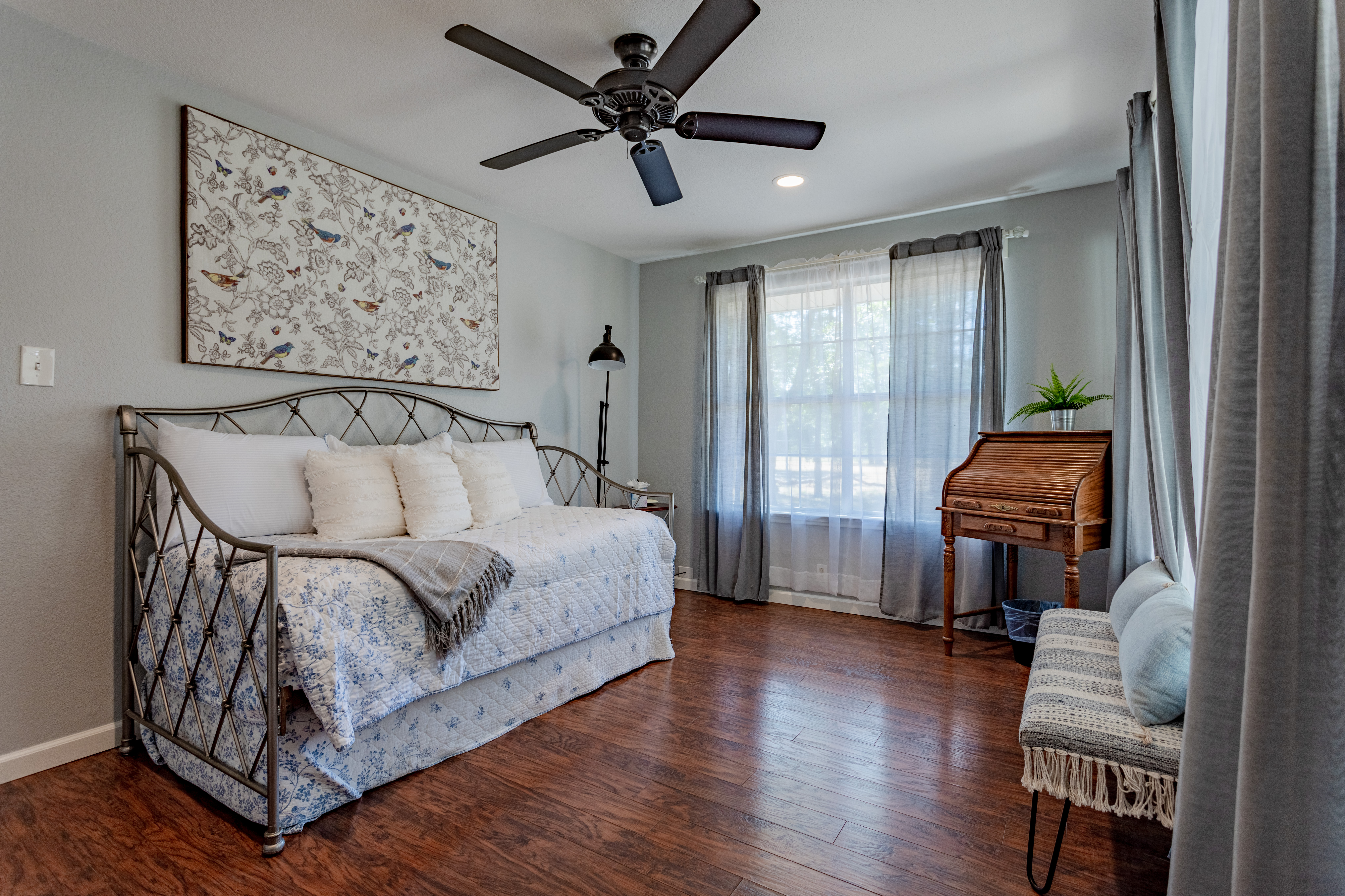 Bright, cozy bedroom with daybed, desk, and abundant natural light