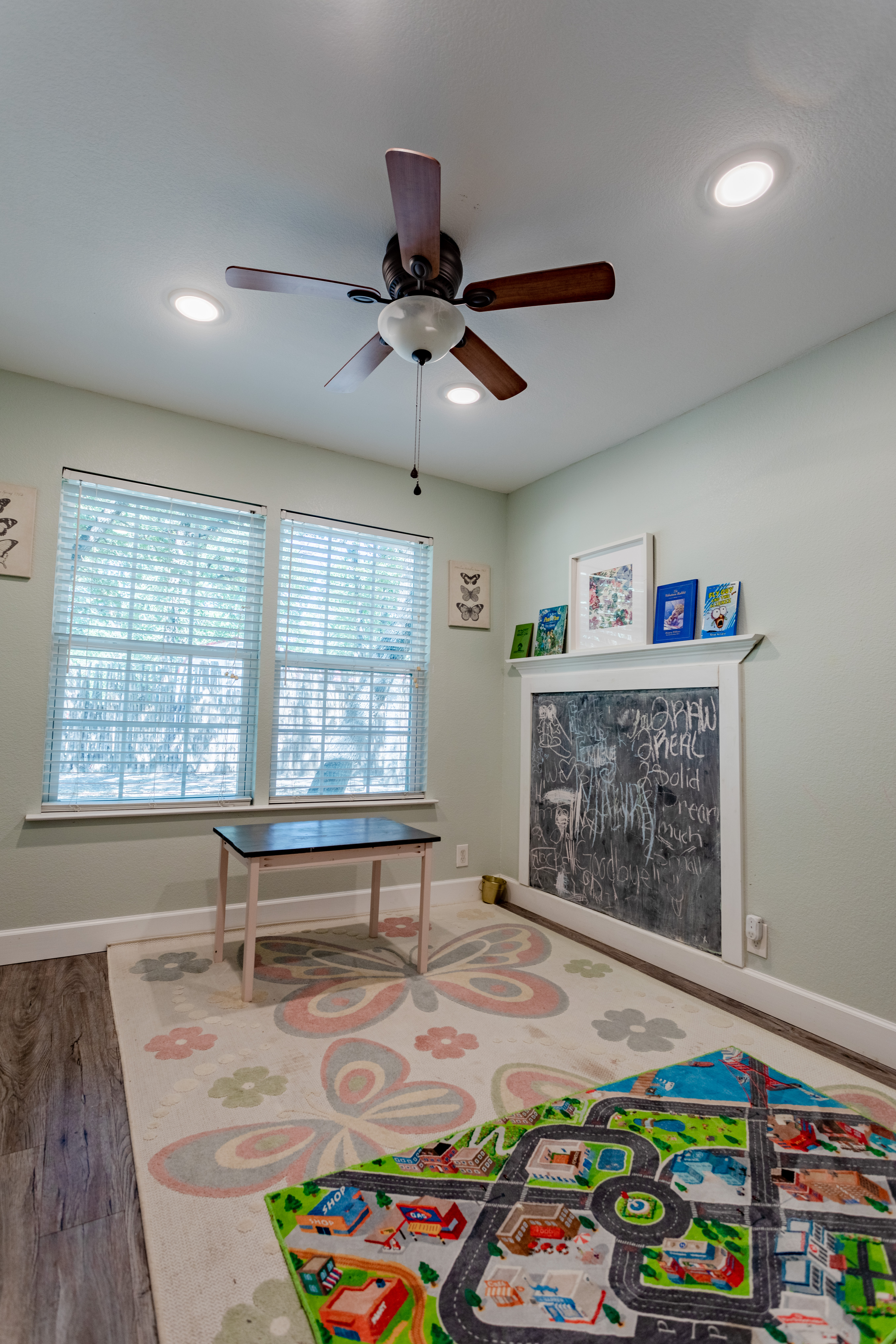 Bright kids’ playroom with chalkboard wall, large windows, and cozy rug