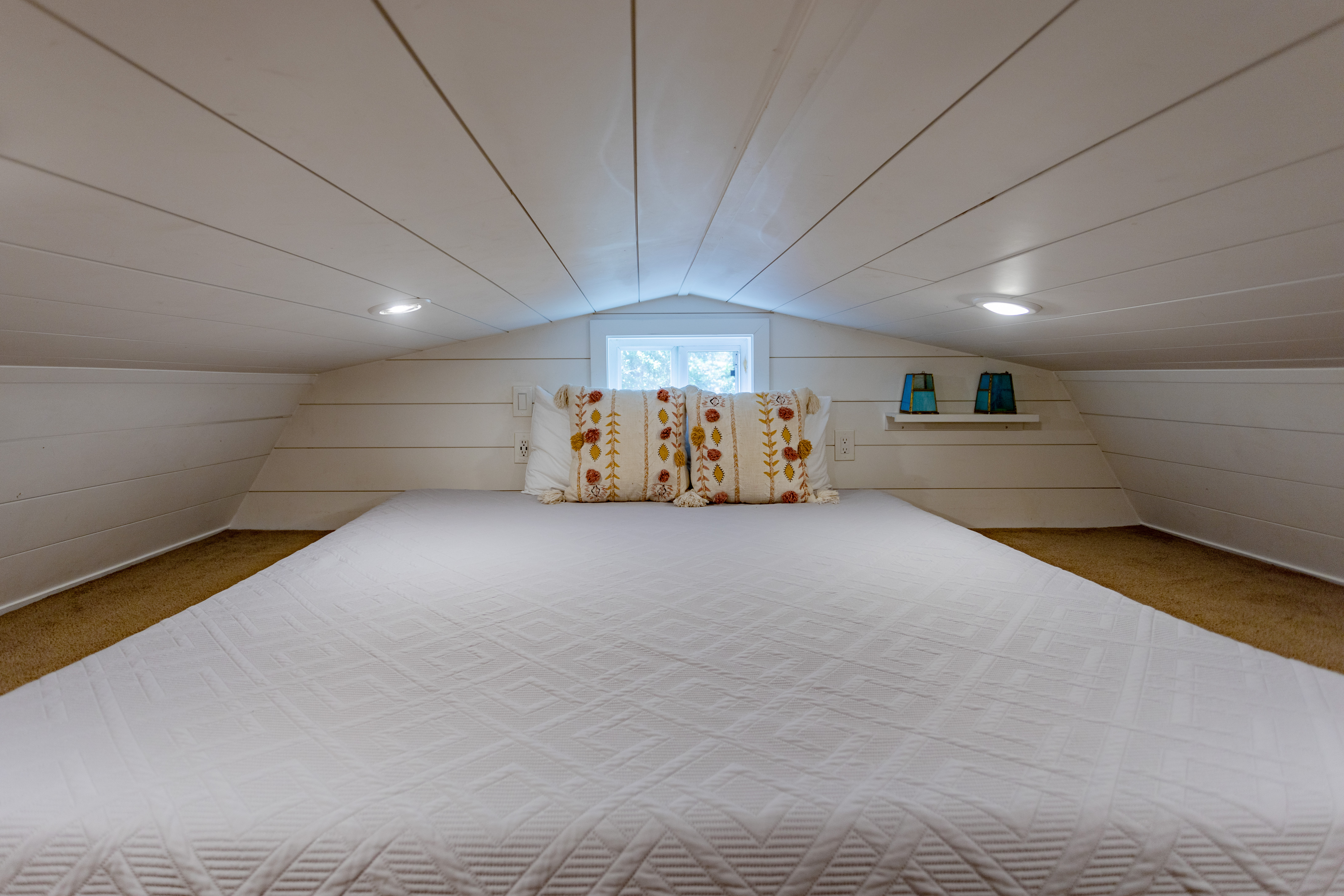 Cozy loft sleeping nook with soft lighting and charming shiplap details