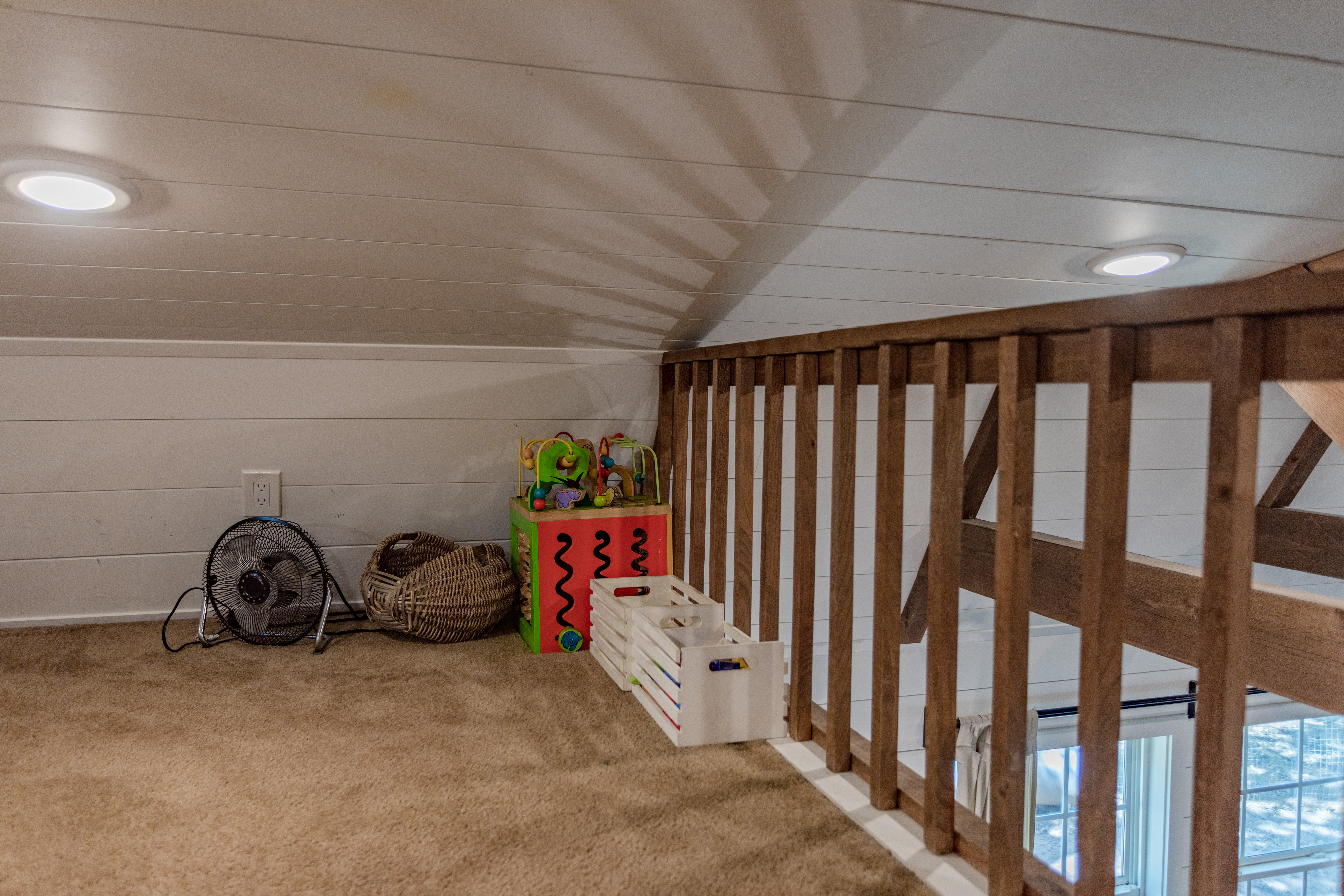 Cozy carpeted loft nook with kid-friendly play space and warm lighting