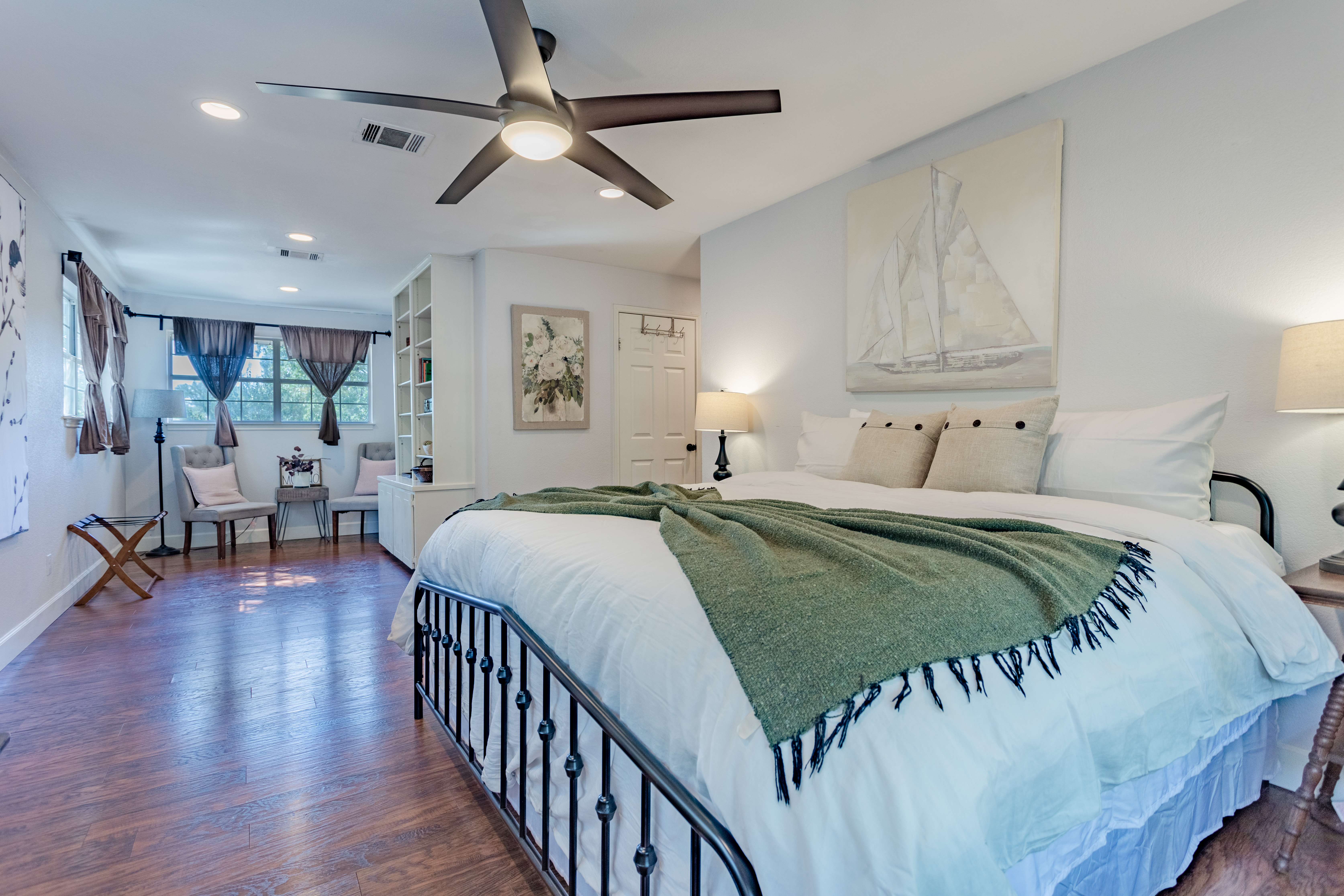 Spacious king bedroom with cozy seating area and warm hardwood floors