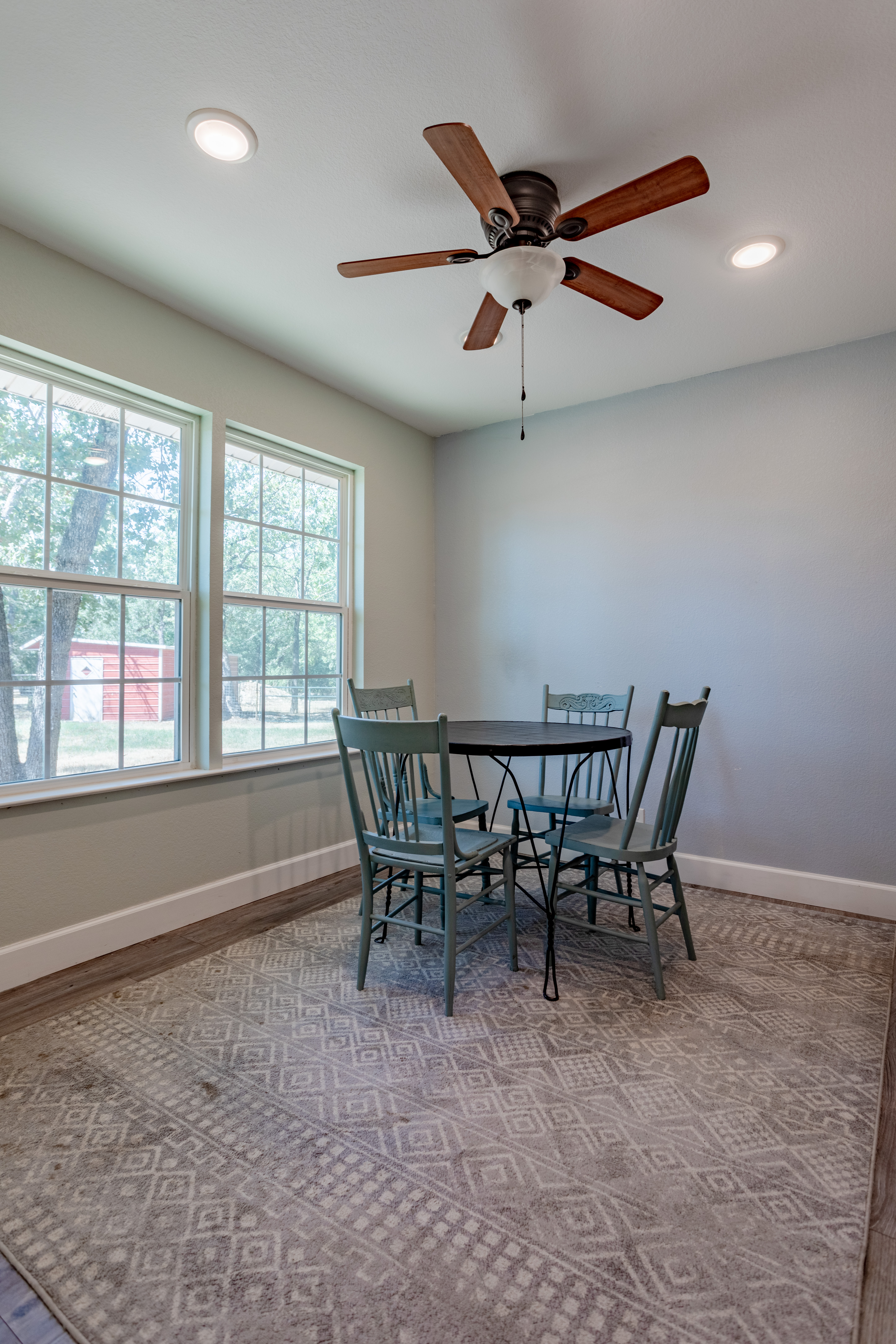 Bright dining nook with big windows, ceiling fan, and seating for four