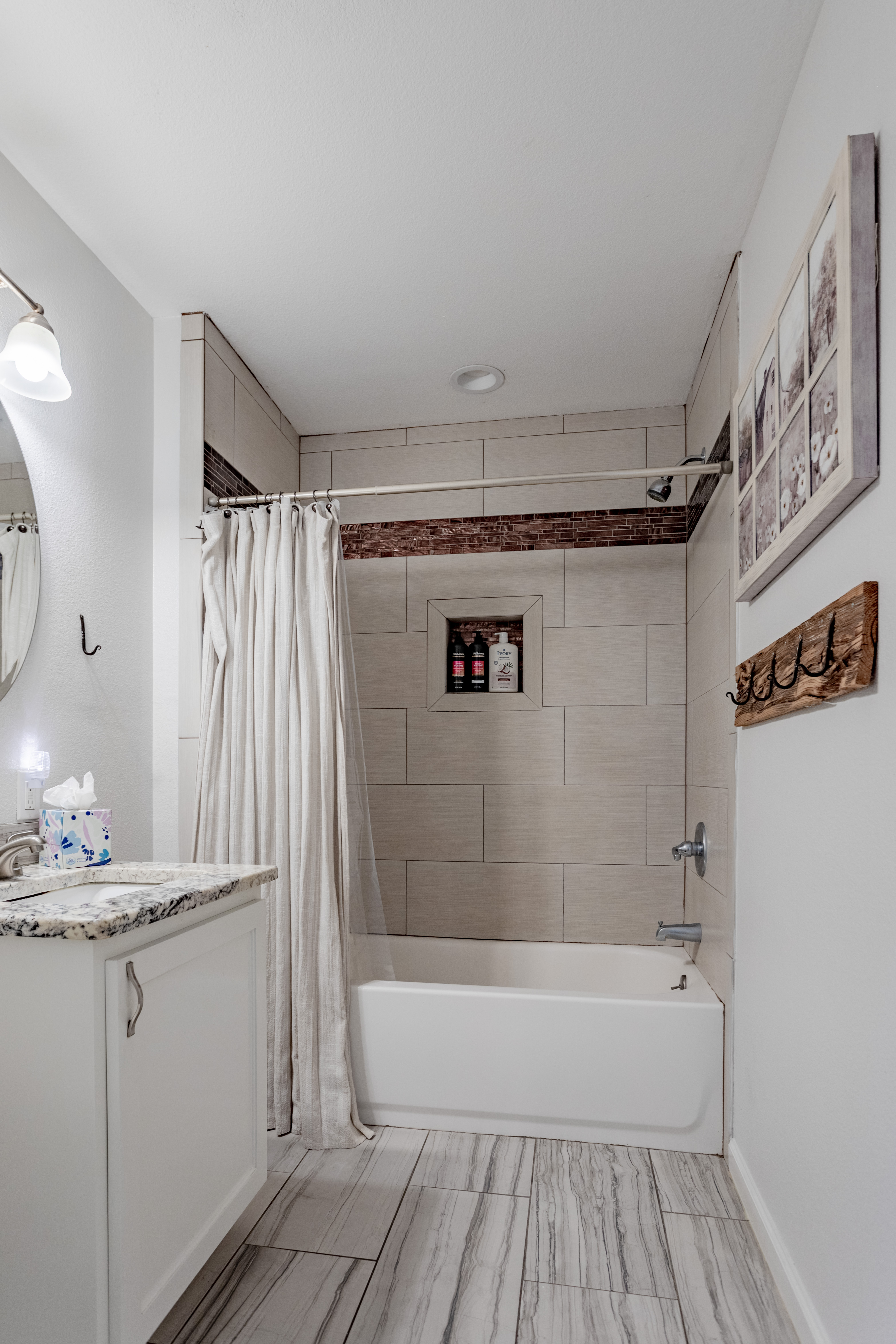 Bright updated bathroom with tiled tub-shower and granite vanity