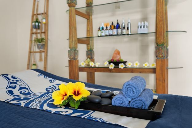 Tranquil spa room with massage bed, hot stones, and tropical touches
