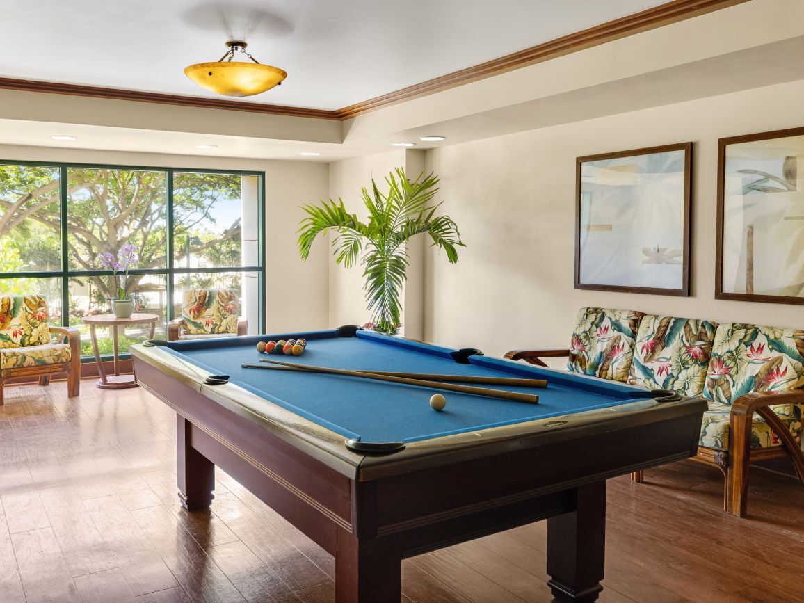 Bright, tropical-style game room with pool table and sunny lounge seating