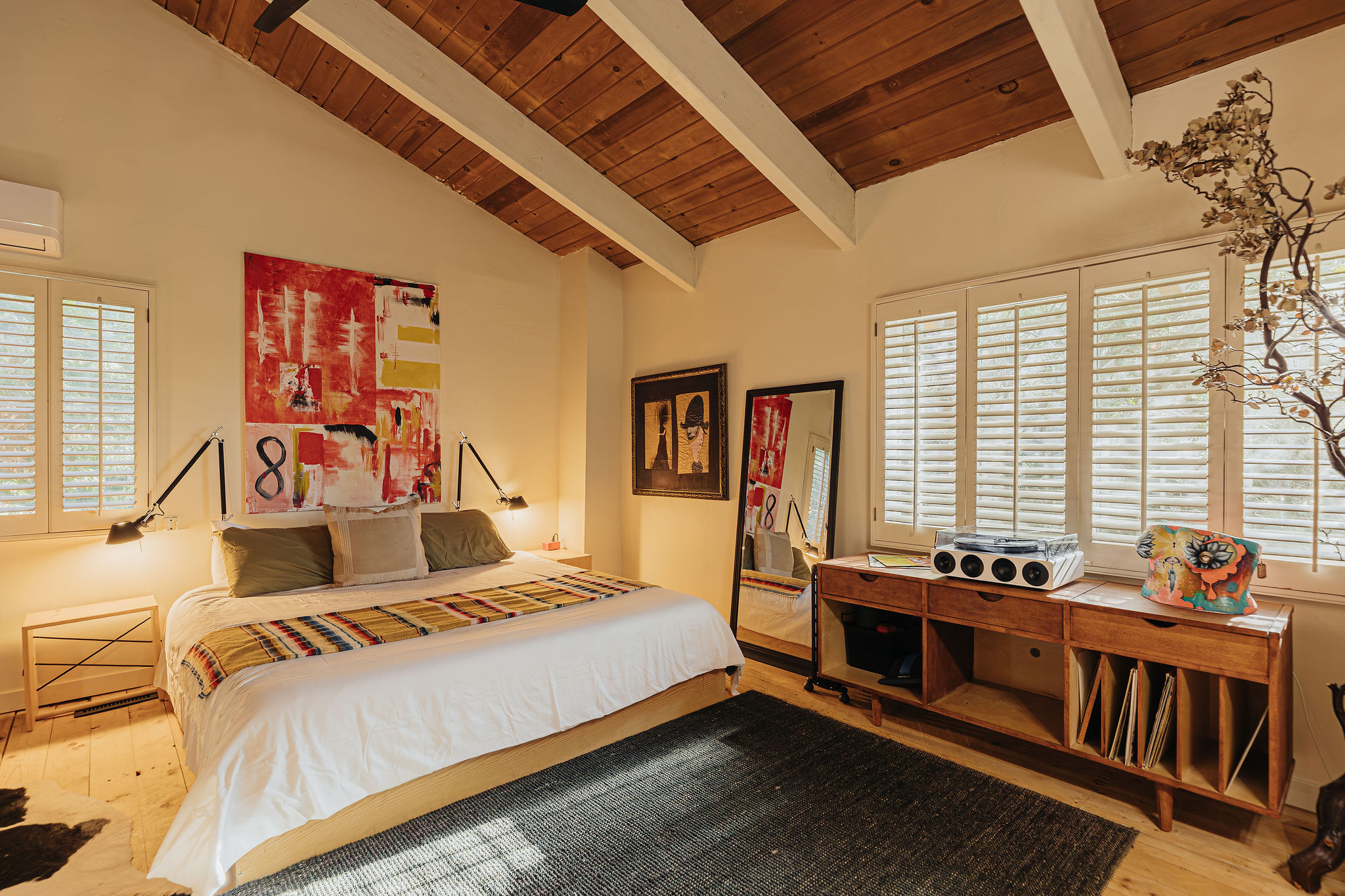 Bright designer bedroom with wood-beamed ceilings and king bed
