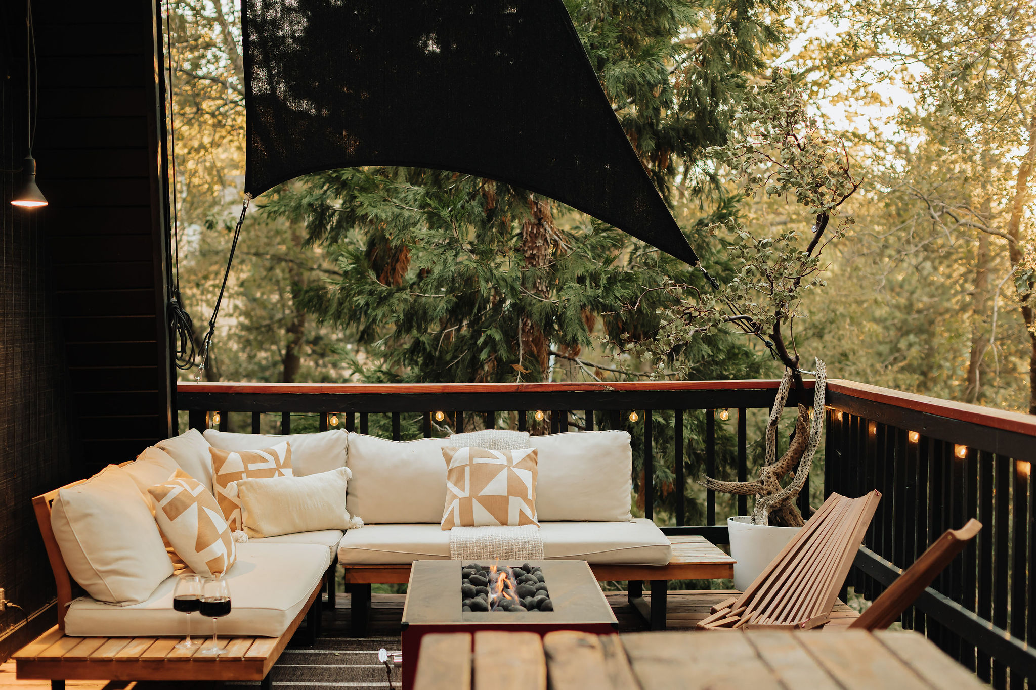 Treehouse-style deck with fire table, lounge seating, and forest views