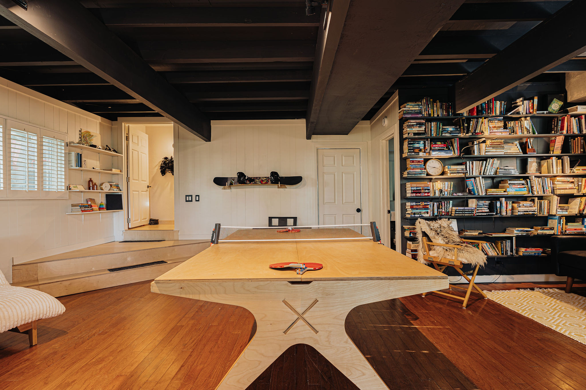 Cozy game room with ping pong, bookshelves, and warm wood accents