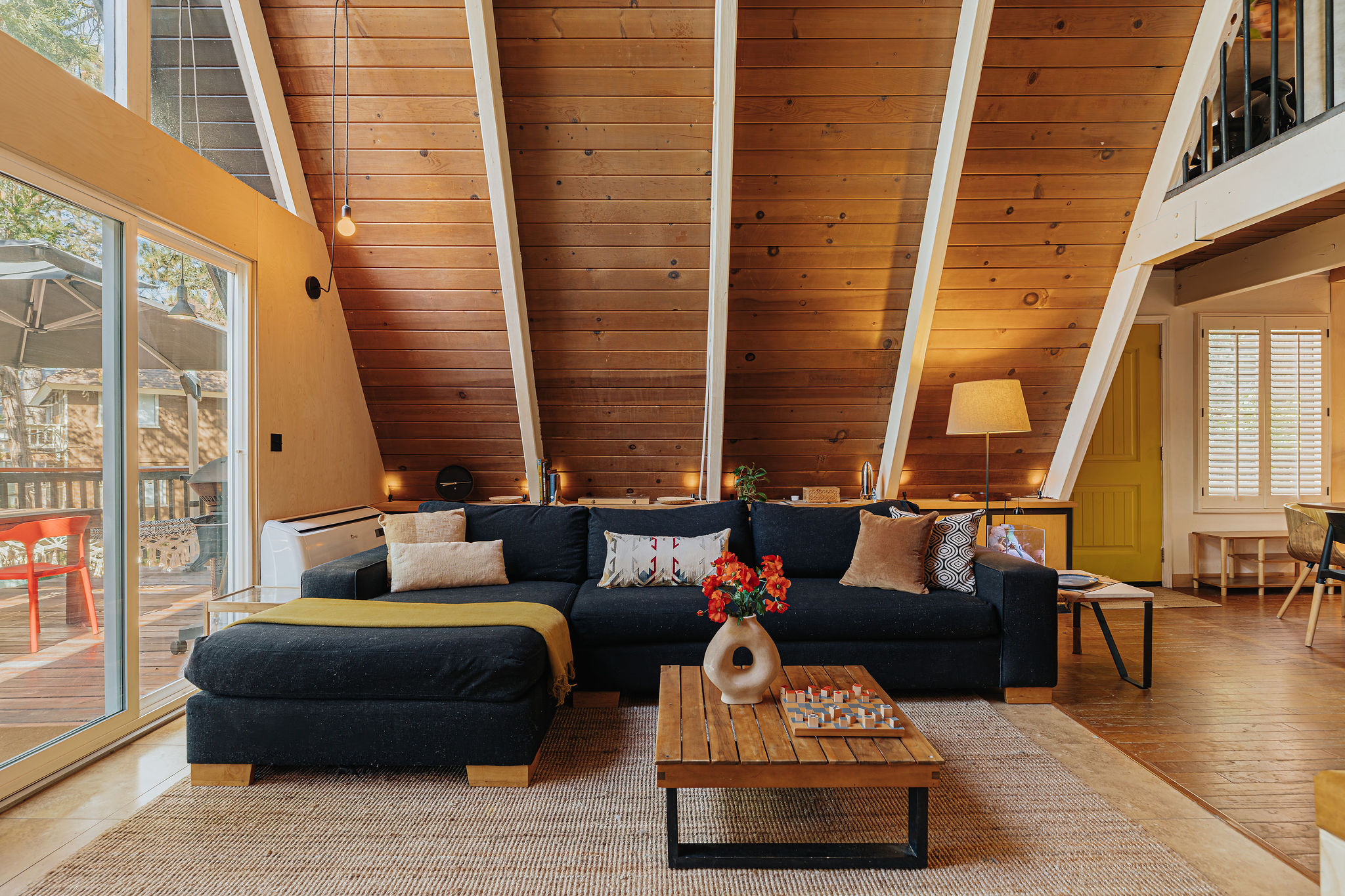 Cozy A-frame living room with vaulted wood ceilings and sunny deck access