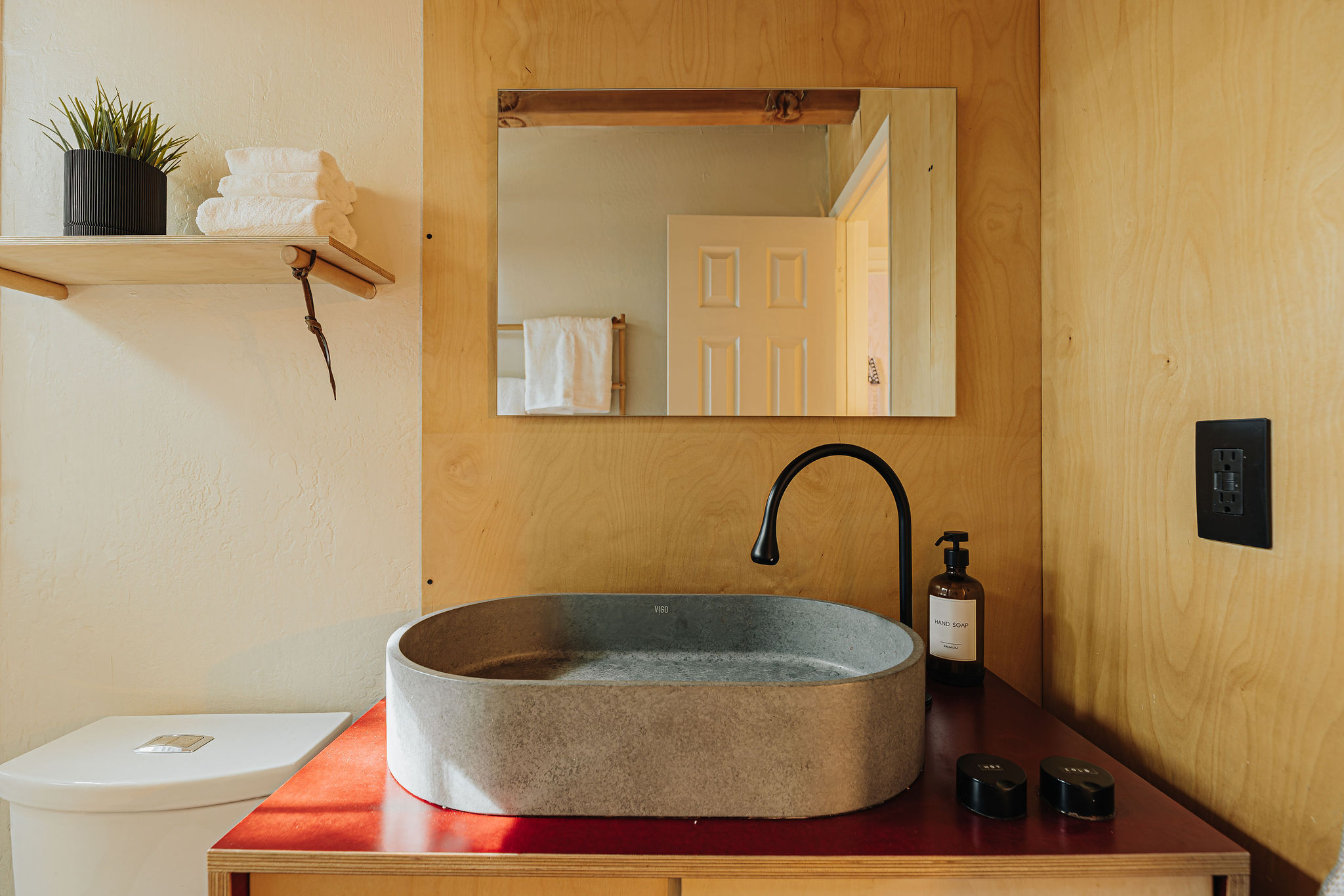 Modern bathroom vanity with stone sink, warm wood accents, and spa-like style