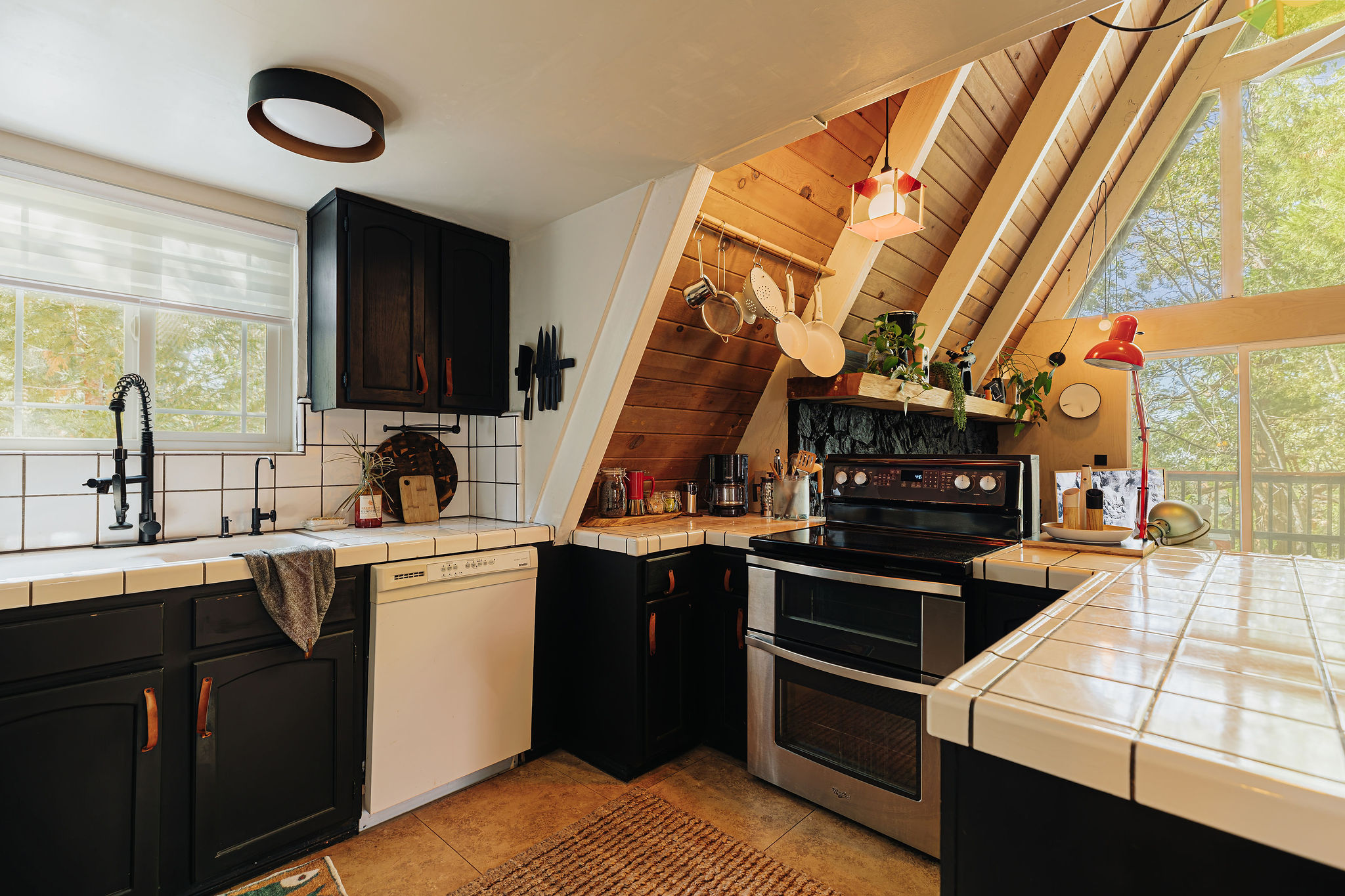 Bright A-frame kitchen with vaulted ceilings and forest-view windows