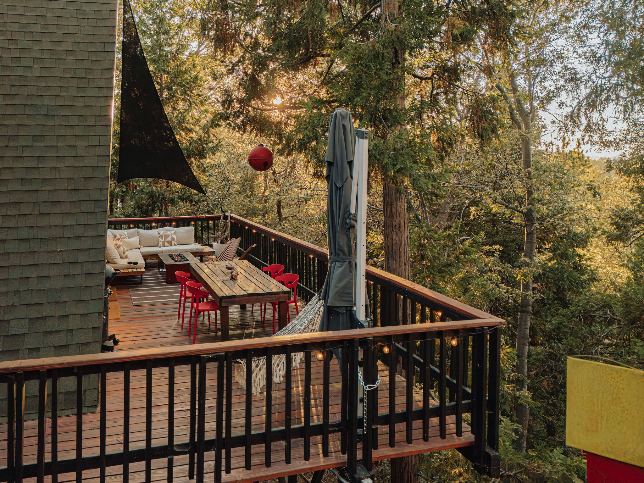Treehouse-style deck with dining, lounge seating, and forest views