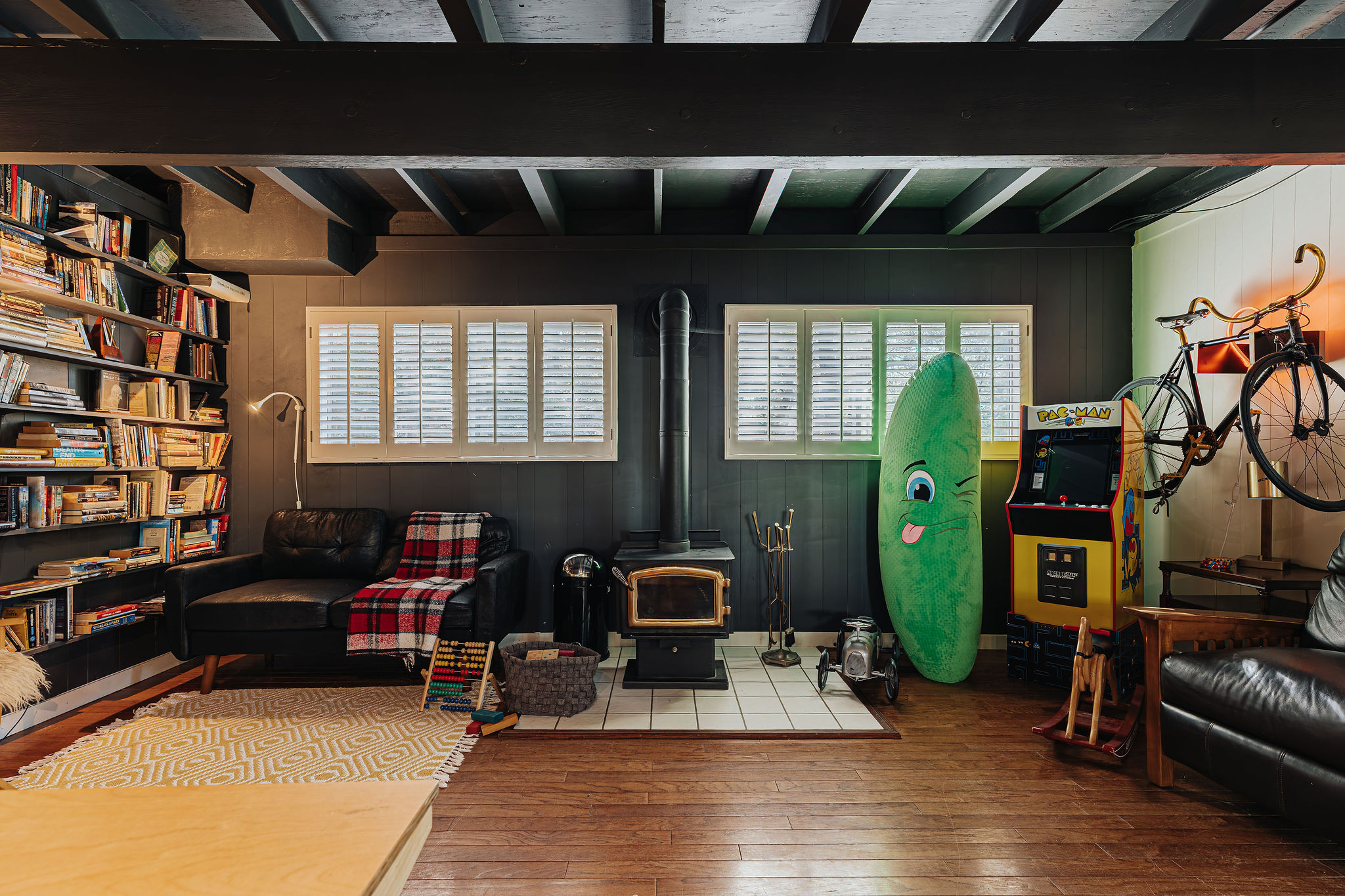 Cozy lounge with wood stove, library wall, and vintage arcade fun