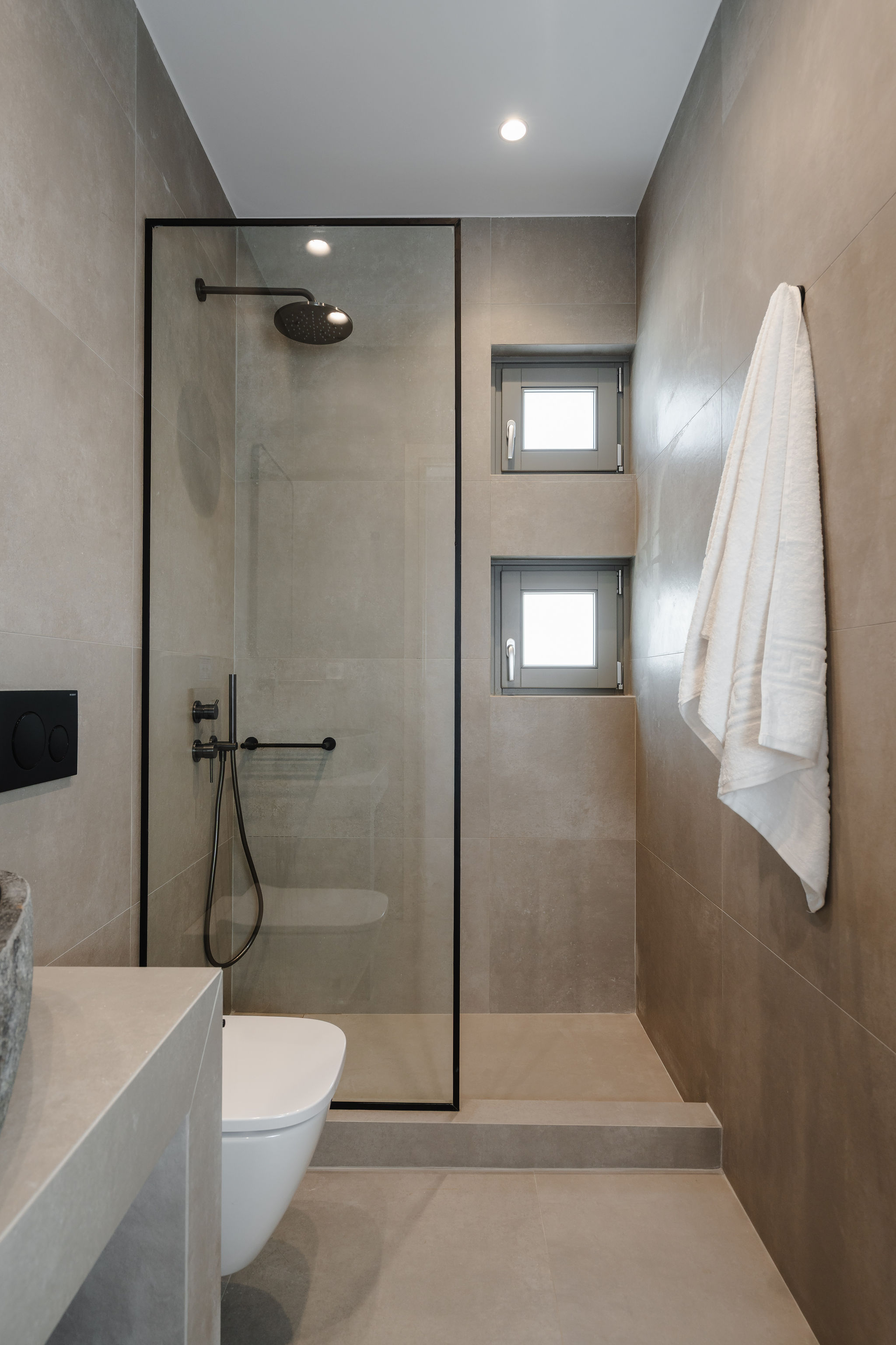 Modern spa-style bathroom with walk-in rain shower and natural light