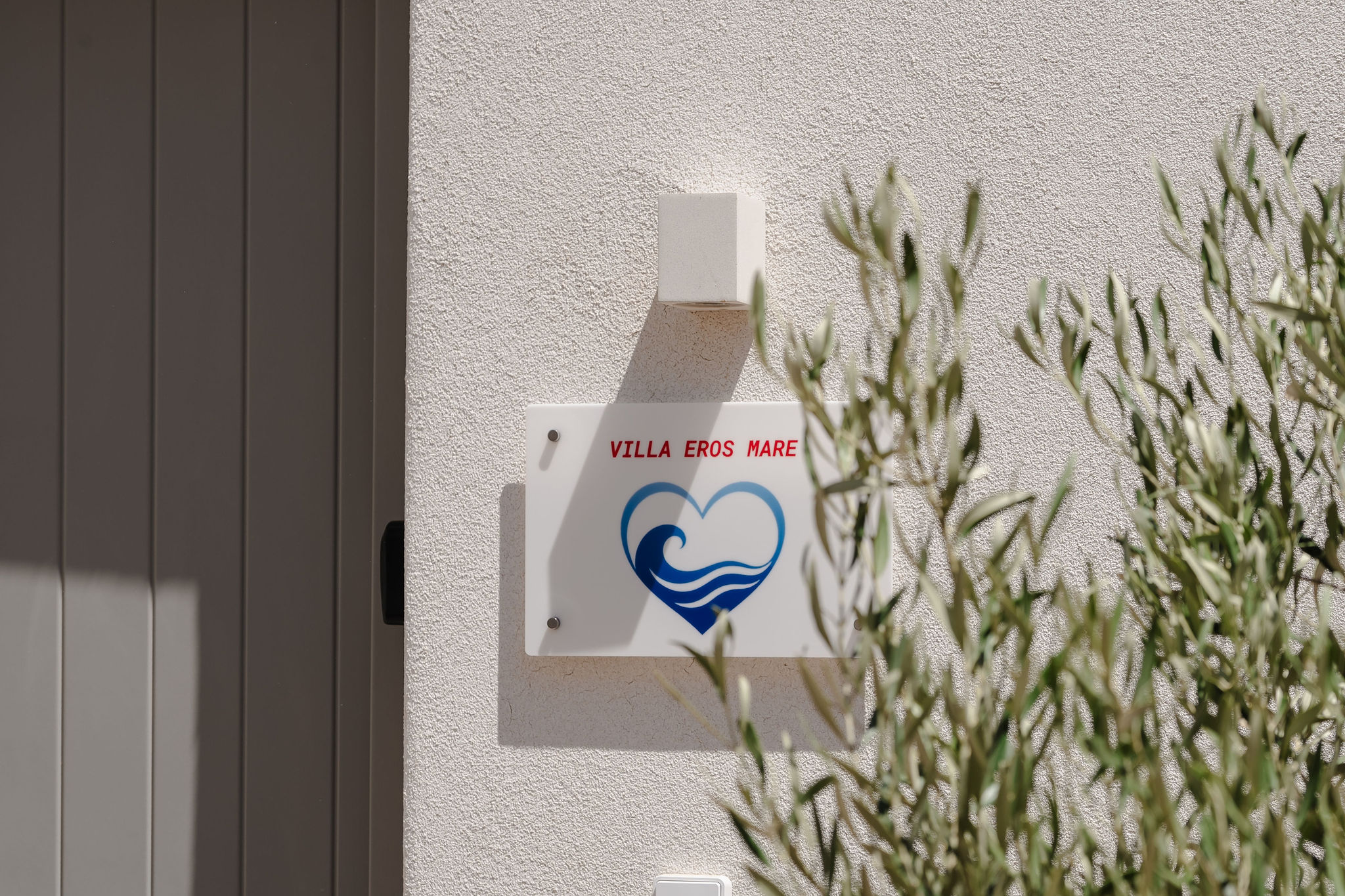 Welcoming villa entrance with charming signage and lush greenery