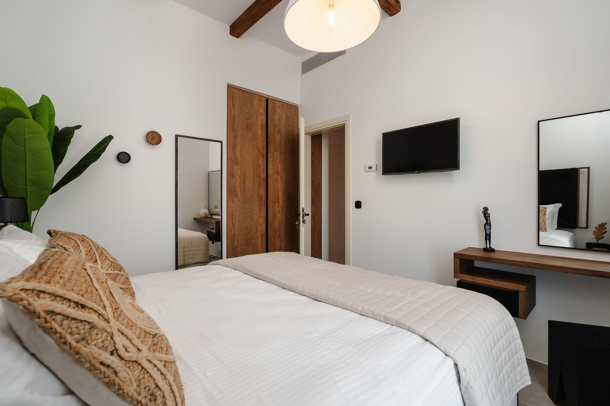 Bright minimalist bedroom with TV, wood accents, and airy high ceilings