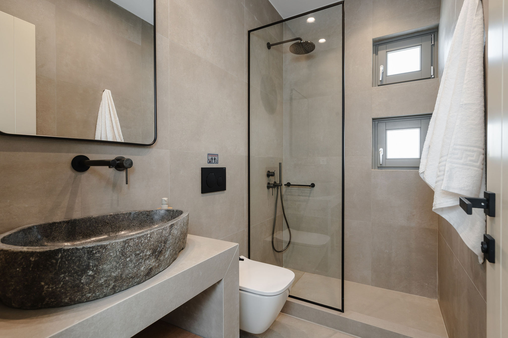 Modern spa-style bathroom with stone sink and glass walk-in shower
