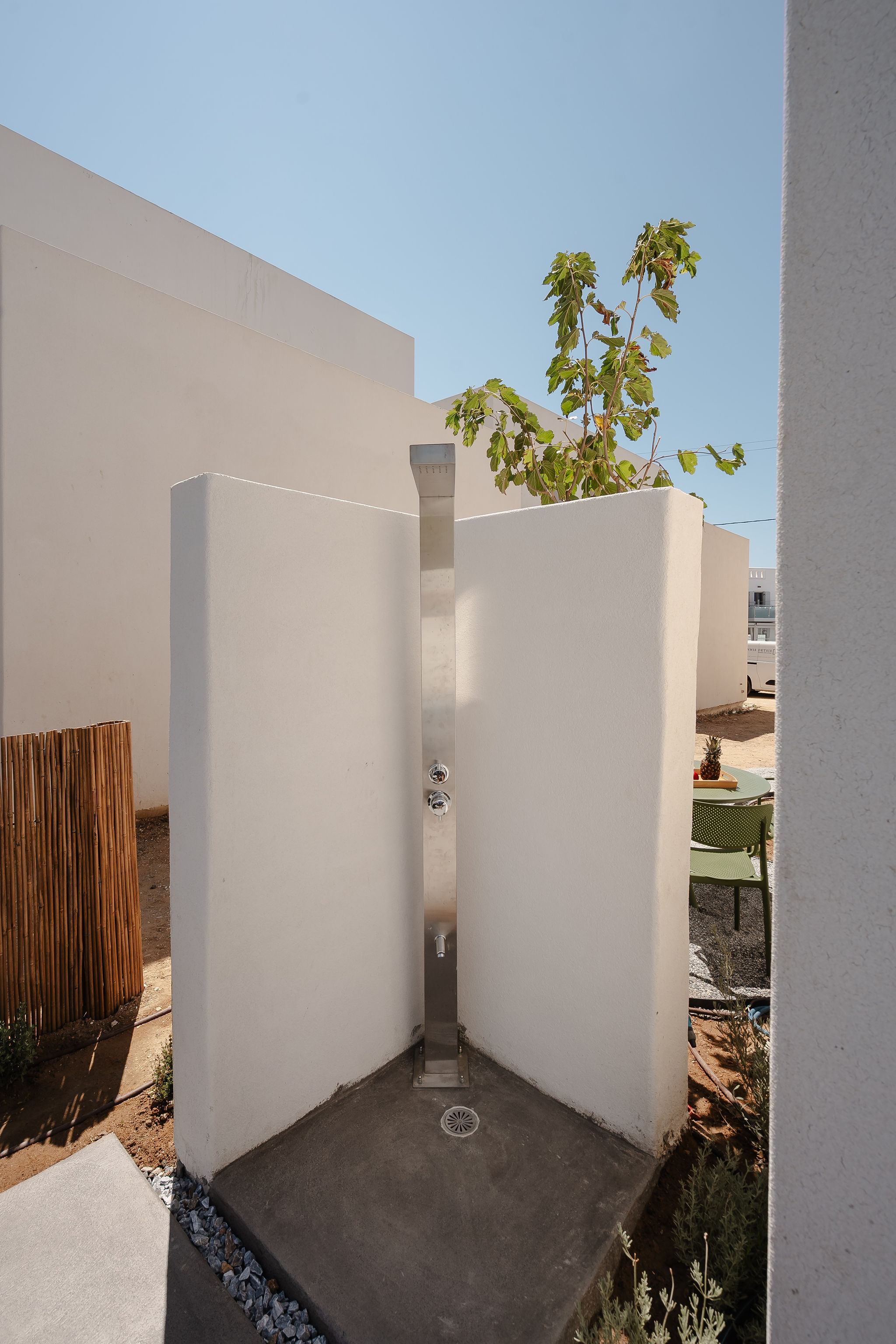 Sunny outdoor shower with private white walls and sleek modern finish