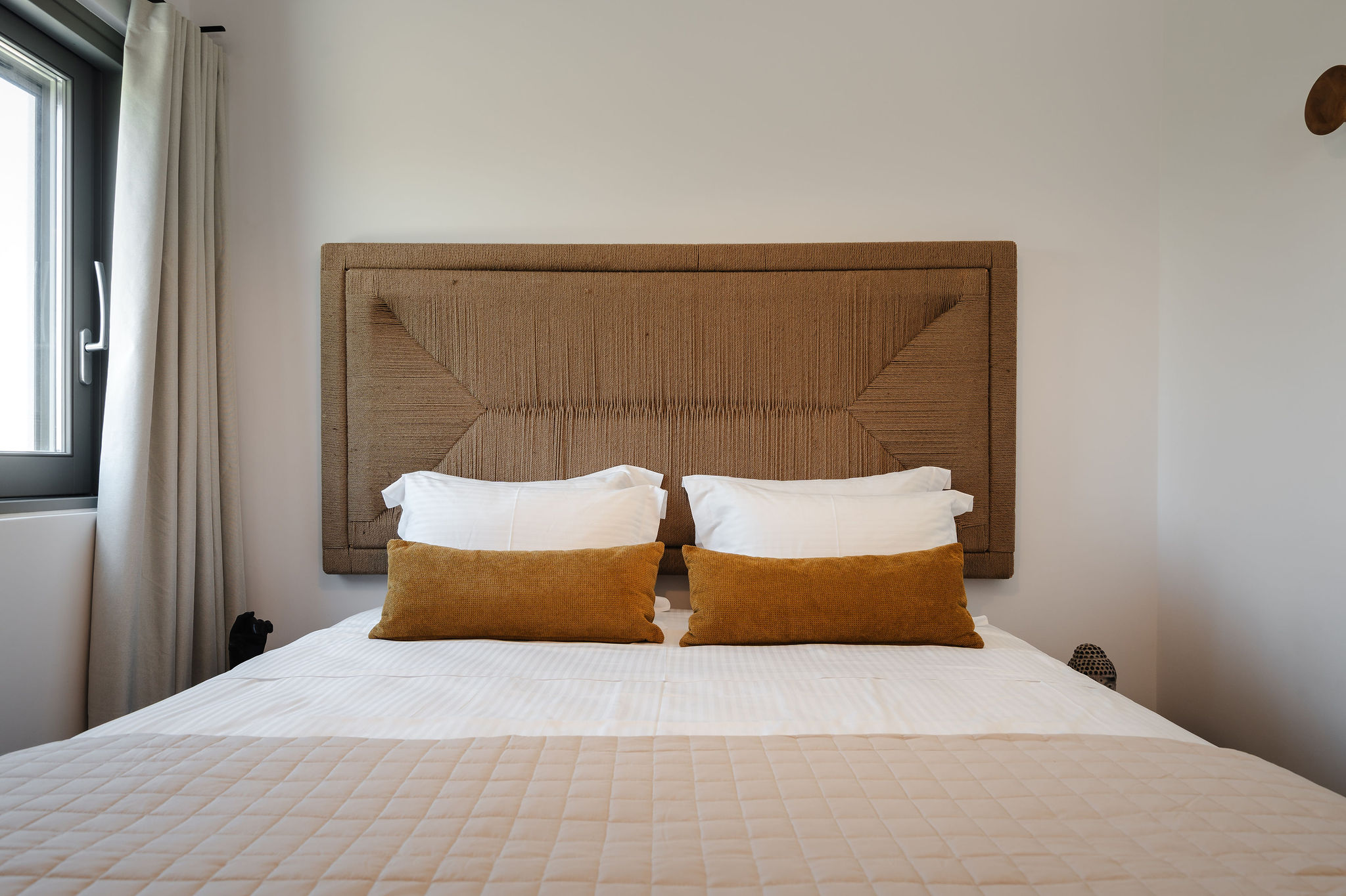 Bright minimalist bedroom with woven headboard and plush king bed