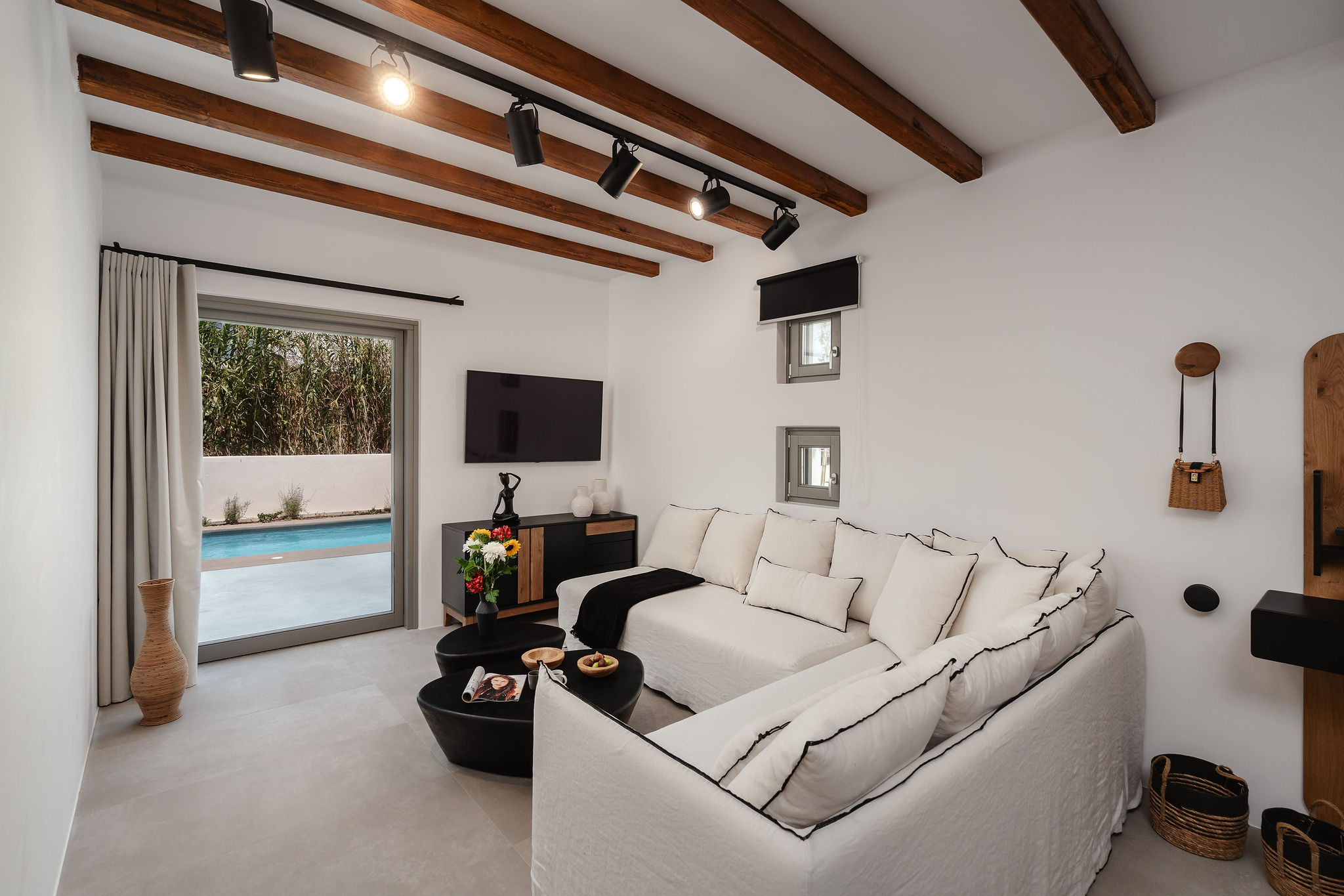 Cozy designer lounge with pool access, exposed beams, and plush seating
