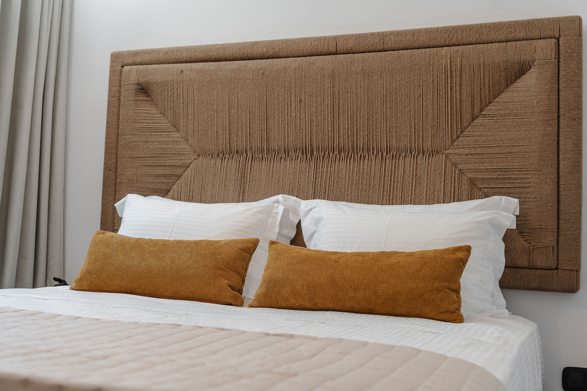 Stylish bedroom with woven headboard and crisp, inviting linens