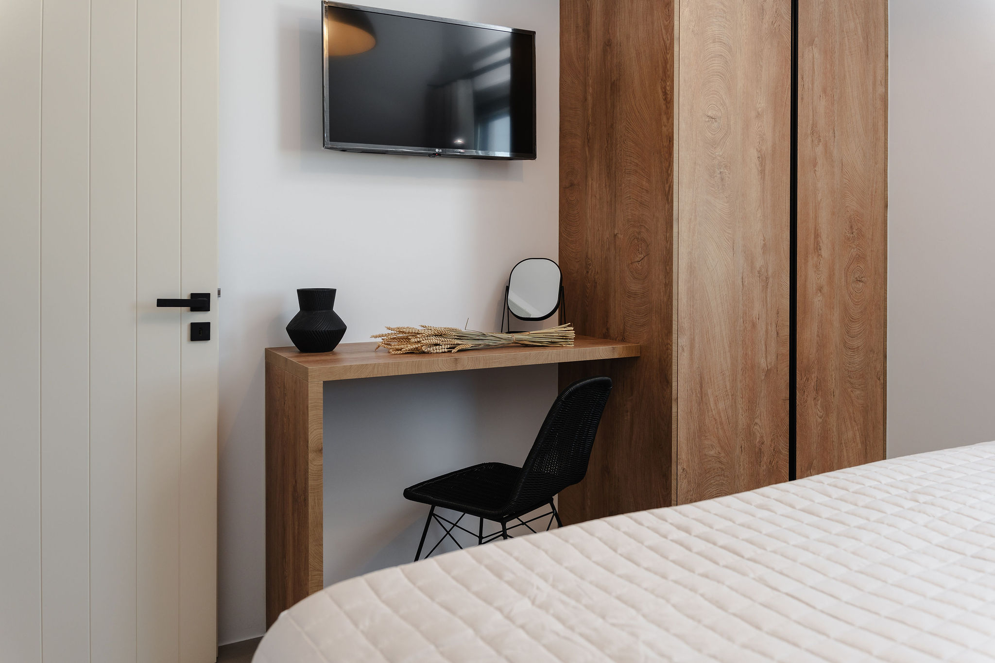 Modern bedroom with TV, wood vanity desk, and spacious wardrobe