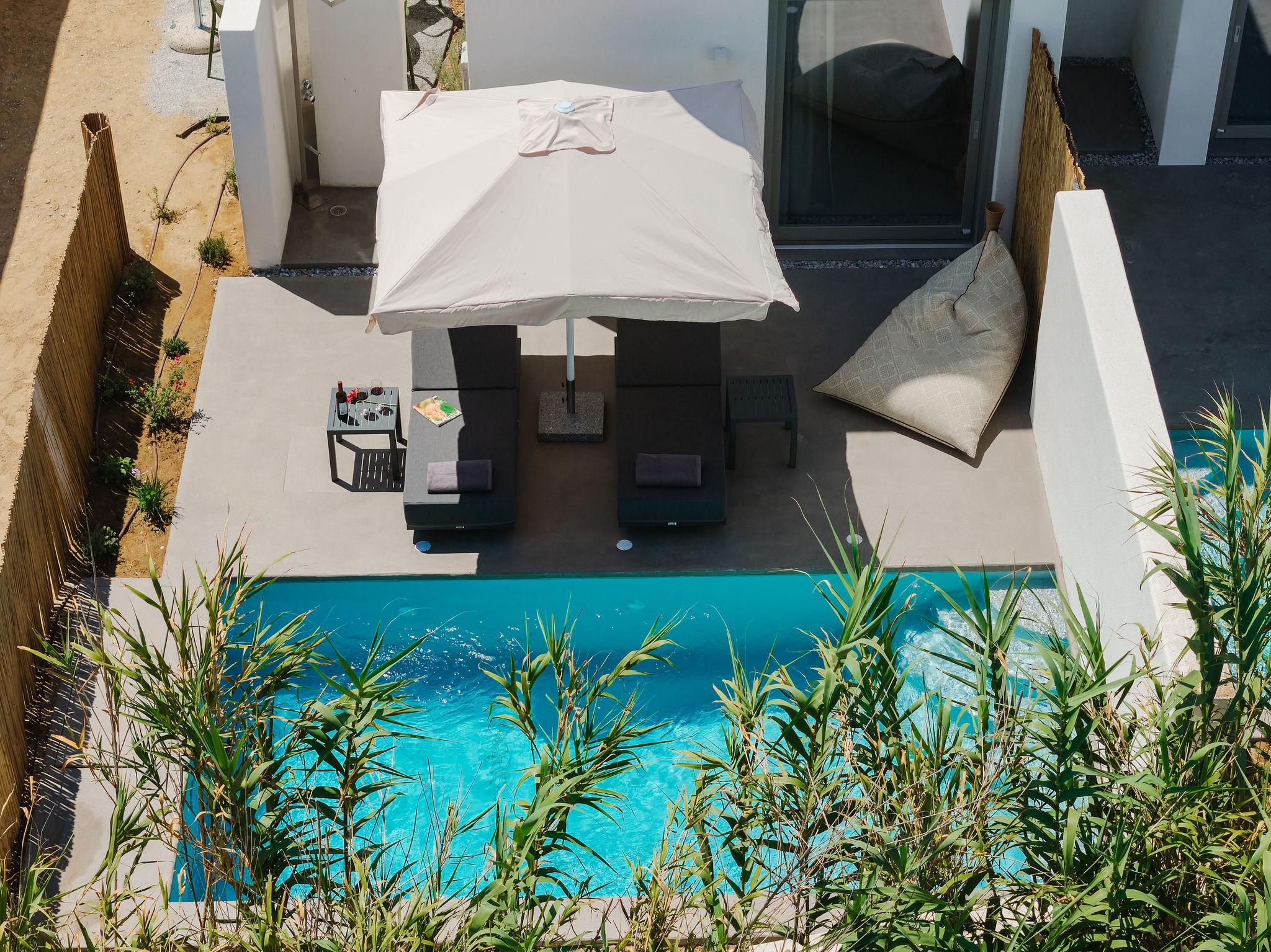 Private plunge pool patio with loungers, shade umbrella, and modern style