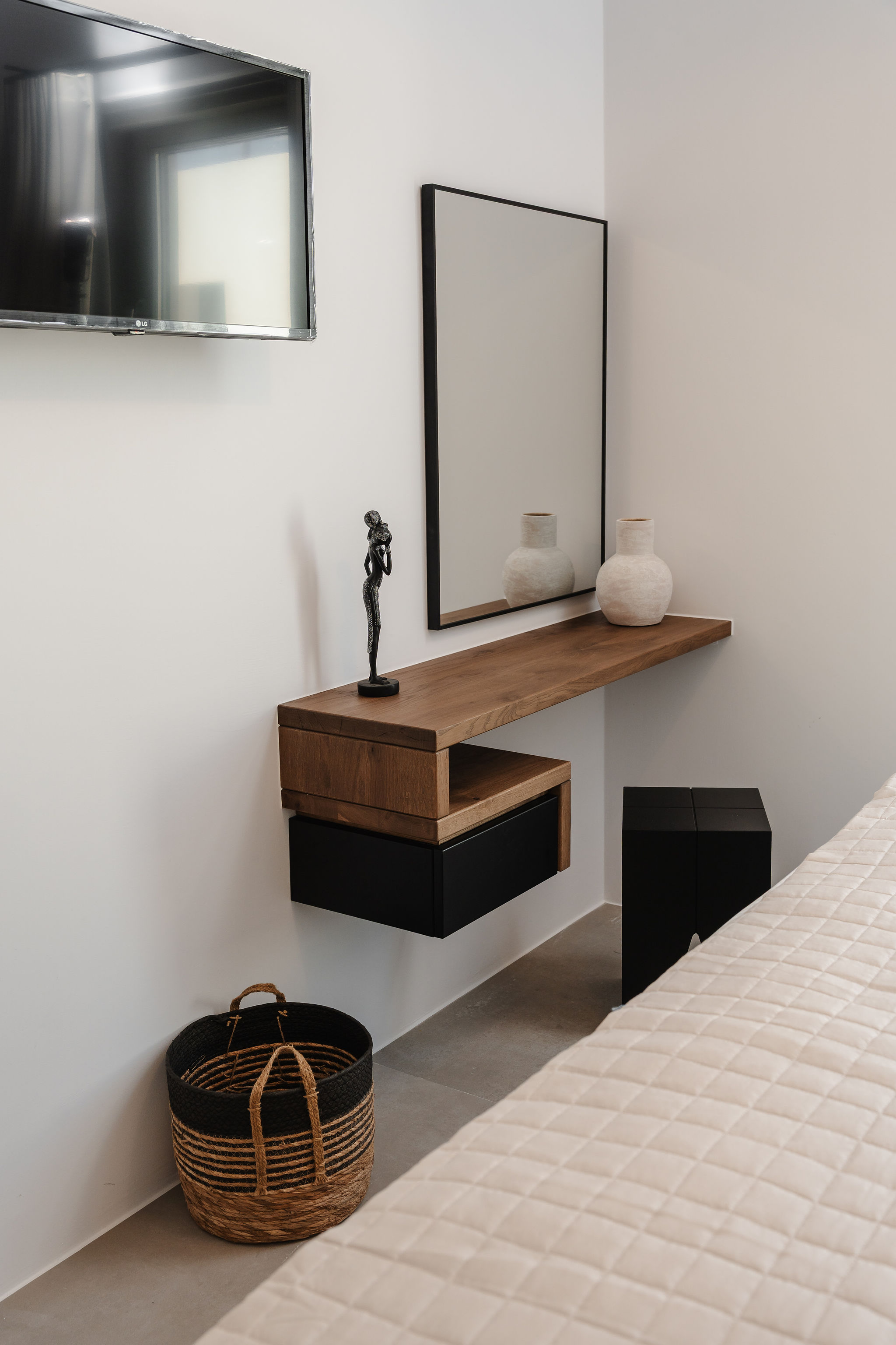 Minimalist bedroom nook with floating vanity, mirror, and wall-mounted TV