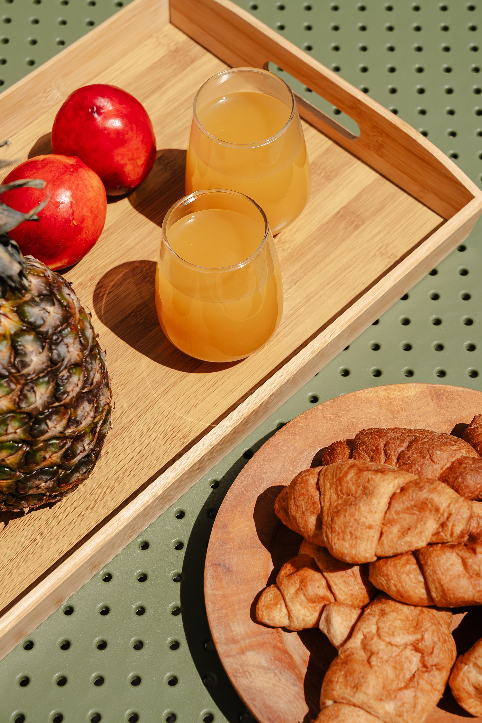 Fresh breakfast spread with juice, fruit, and flaky croissants in sunny style