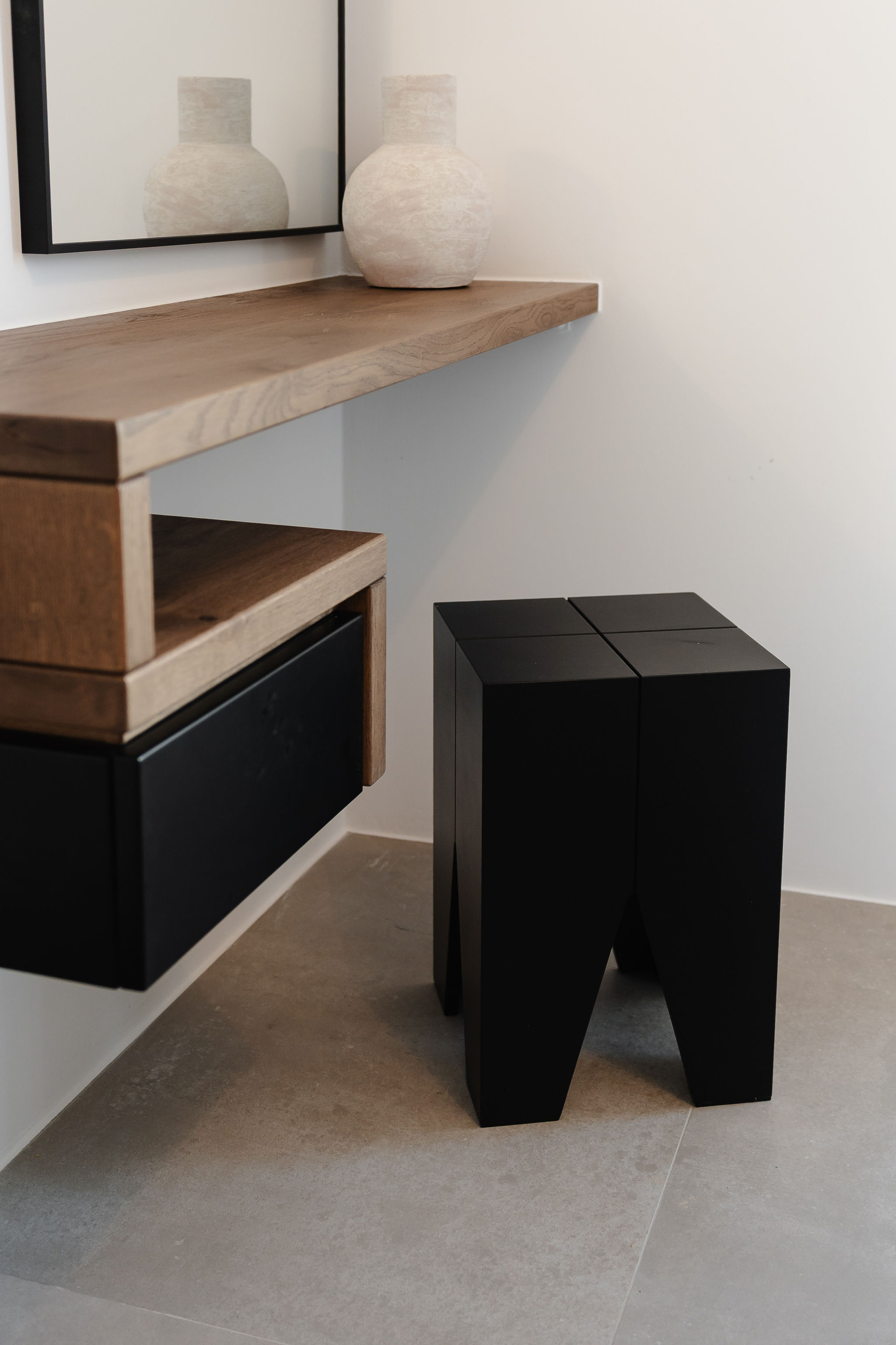 Modern floating vanity with sculptural stool and warm wood accents