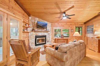 Real wood crackles in the stacked-stone fireplace beneath the mounted TV, pine walls glow warm on every side, and the deep sofa is exactly where you'll end up after a day outside.