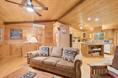 Step in the side door and you're already in the living space — wildlife-print pillows on the sofa, a mini-split for year-round comfort, and an open sightline all the way to the kitchen island.