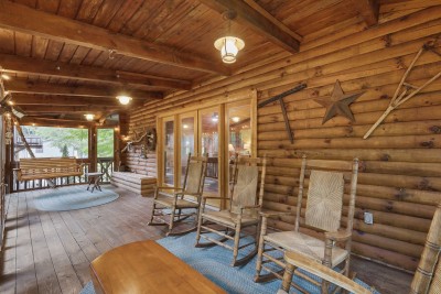 String lights glow along the beams, rush-seat rockers line the log wall, and a wooden swing waits at the far end — pick a seat and watch the trees do the rest.