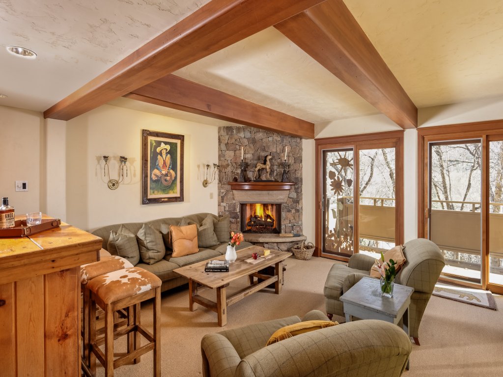 Cozy lodge-style living room with stone fireplace and scenic forest views