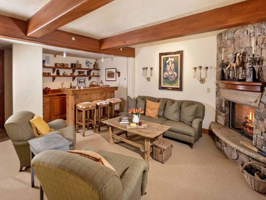 Cozy rustic lounge with stone fireplace and charming wet bar