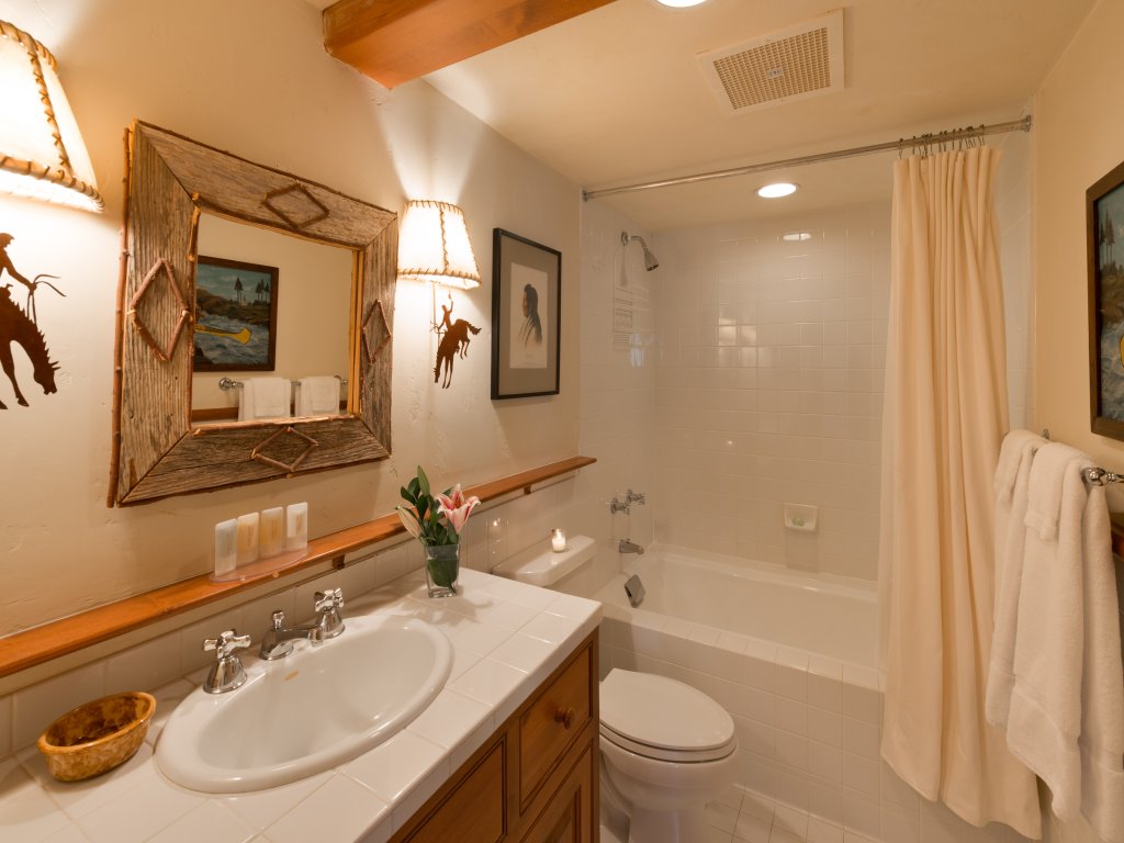 Rustic full bathroom with tub-shower combo and warm western charm