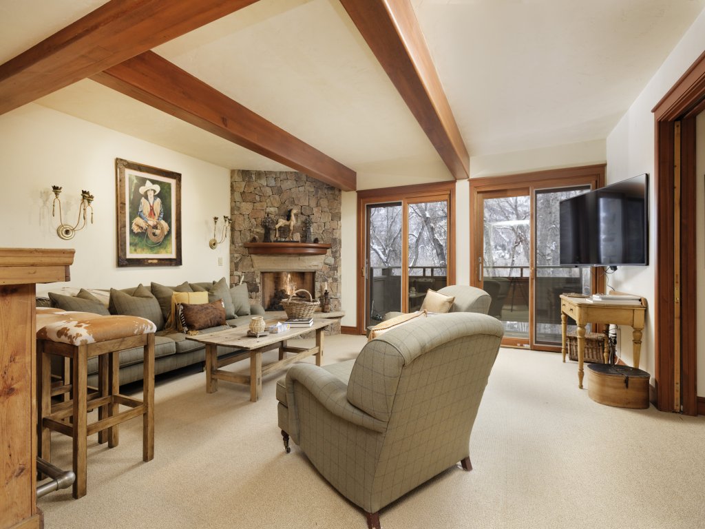 Cozy mountain-style living room with stone fireplace and private balcony