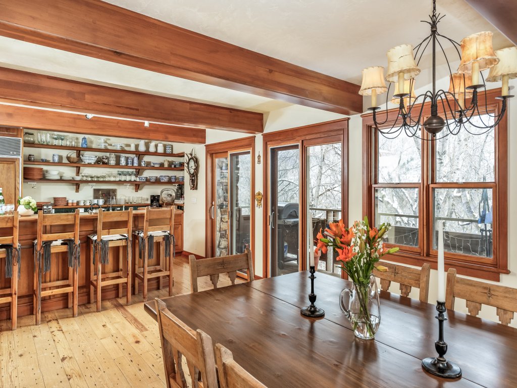 Rustic dining room with wood beams, breakfast bar, and snowy views