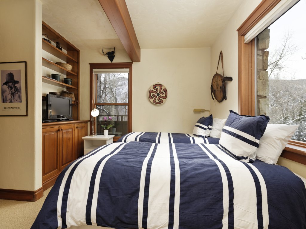 Cozy bedroom with large windows, warm wood accents, and serene views