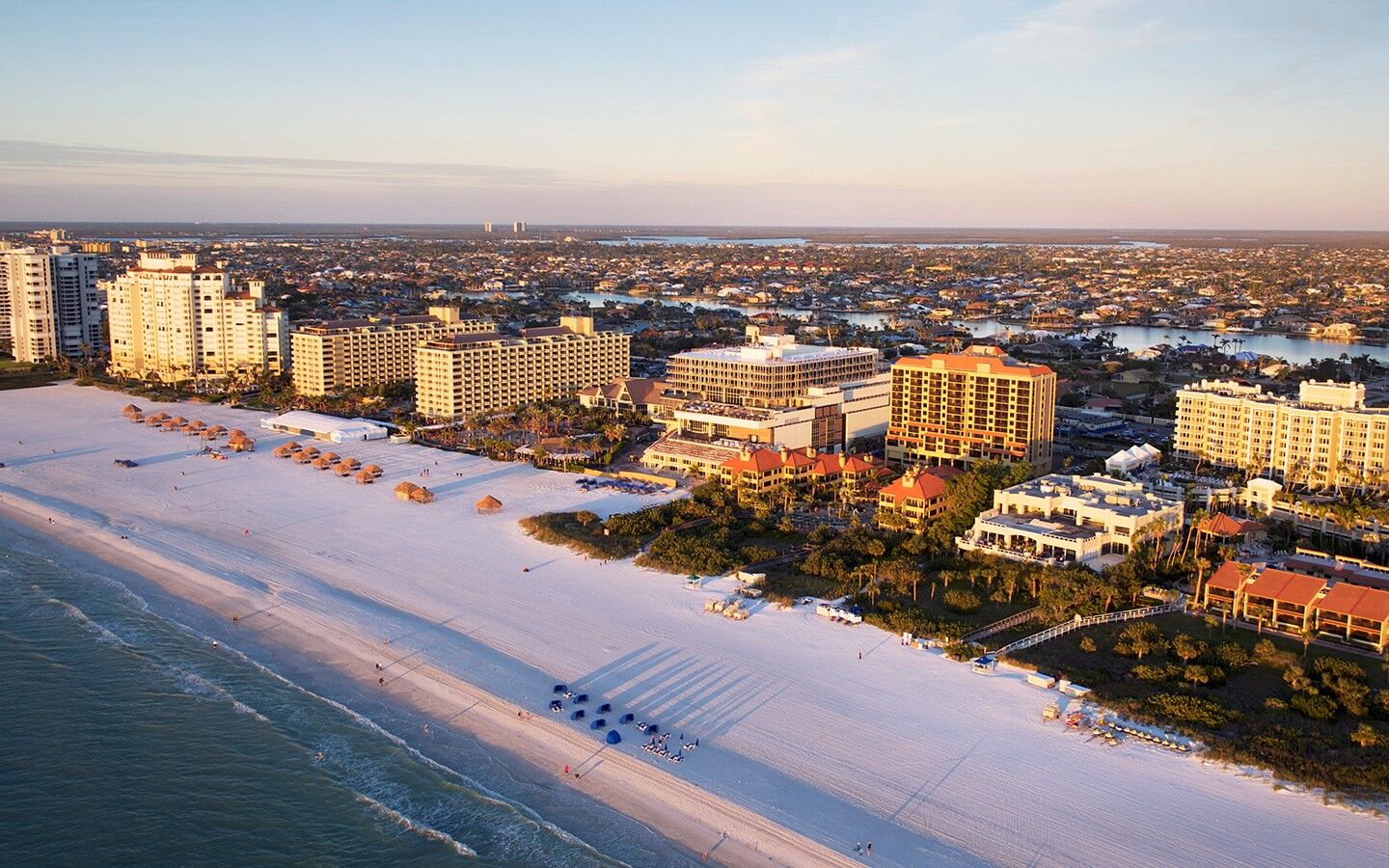 Sweeping aerial view of white-sand beach and vibrant beachfront resorts