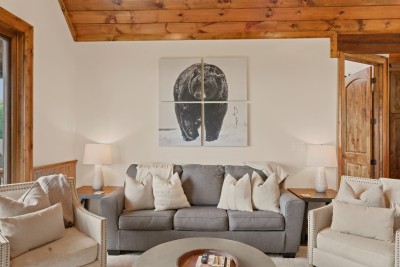A four-panel black-and-white bear photograph anchors this lounge, where a gray sofa and two nailhead armchairs gather around a round wood coffee table.