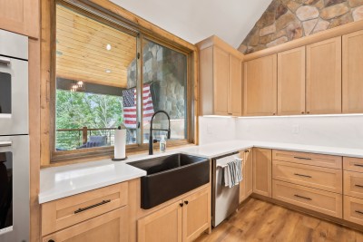 A farmhouse sink under the window keeps kitchen prep with a view, wash dishes while you watch the tree line.