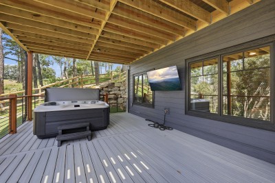 Covered deck with a private hot tub, TV, and peaceful wooded views. Soak away the whole day, watch your favorite show, or simply take in the quiet surroundings, all from the comfort of your own outdoor escape tucked into the trees of these mountains.