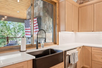 Natural light pours in over the sink, framed by clean quartz counters and classic gold hardware.
