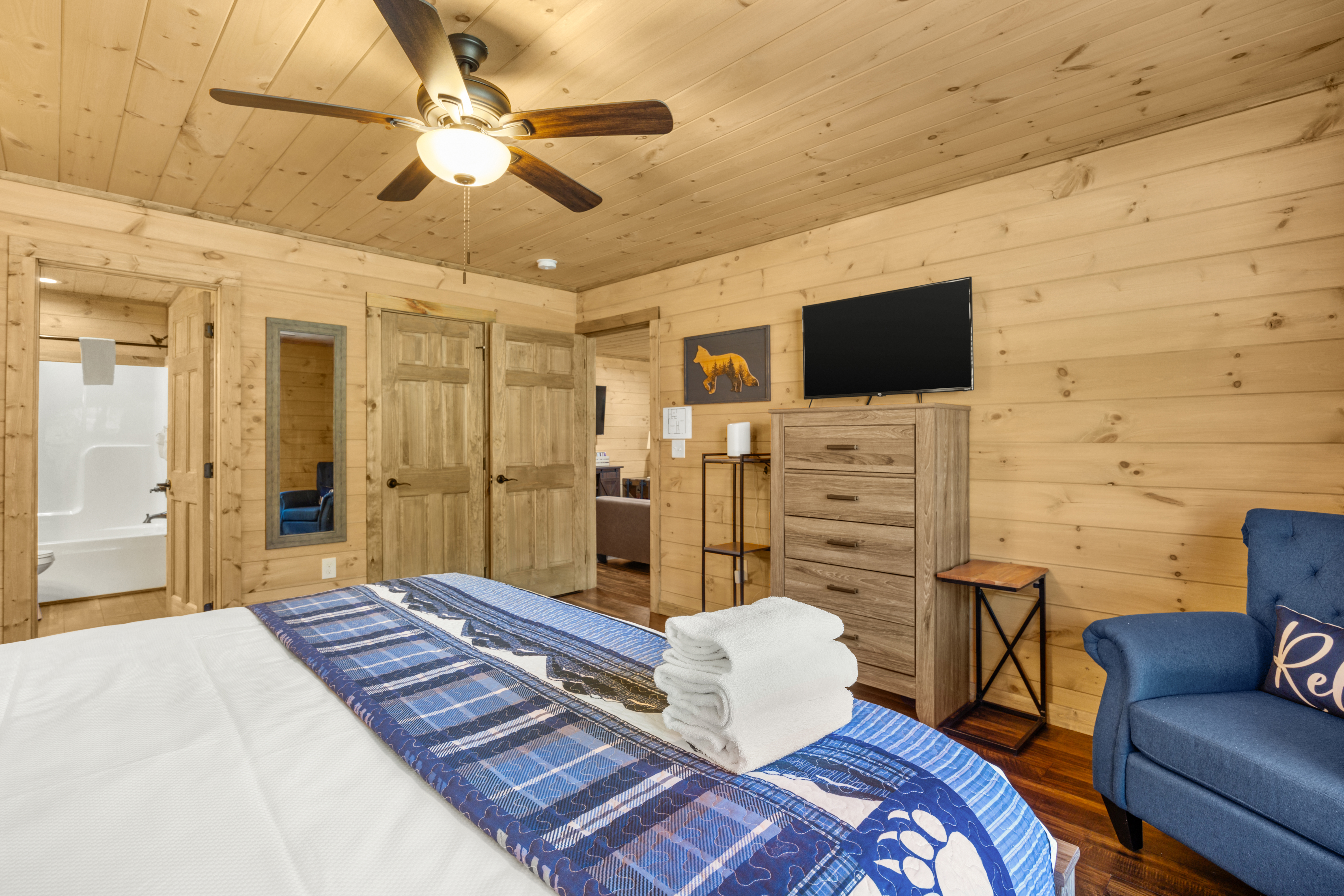Cozy wood-paneled bedroom with TV, seating, and rustic cabin charm